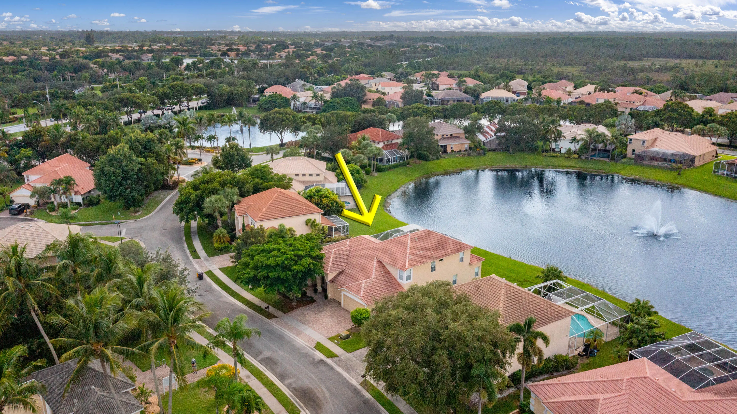 Waterfront property featuring a private screened pool enclosure, mature landscaping, and a tile roof