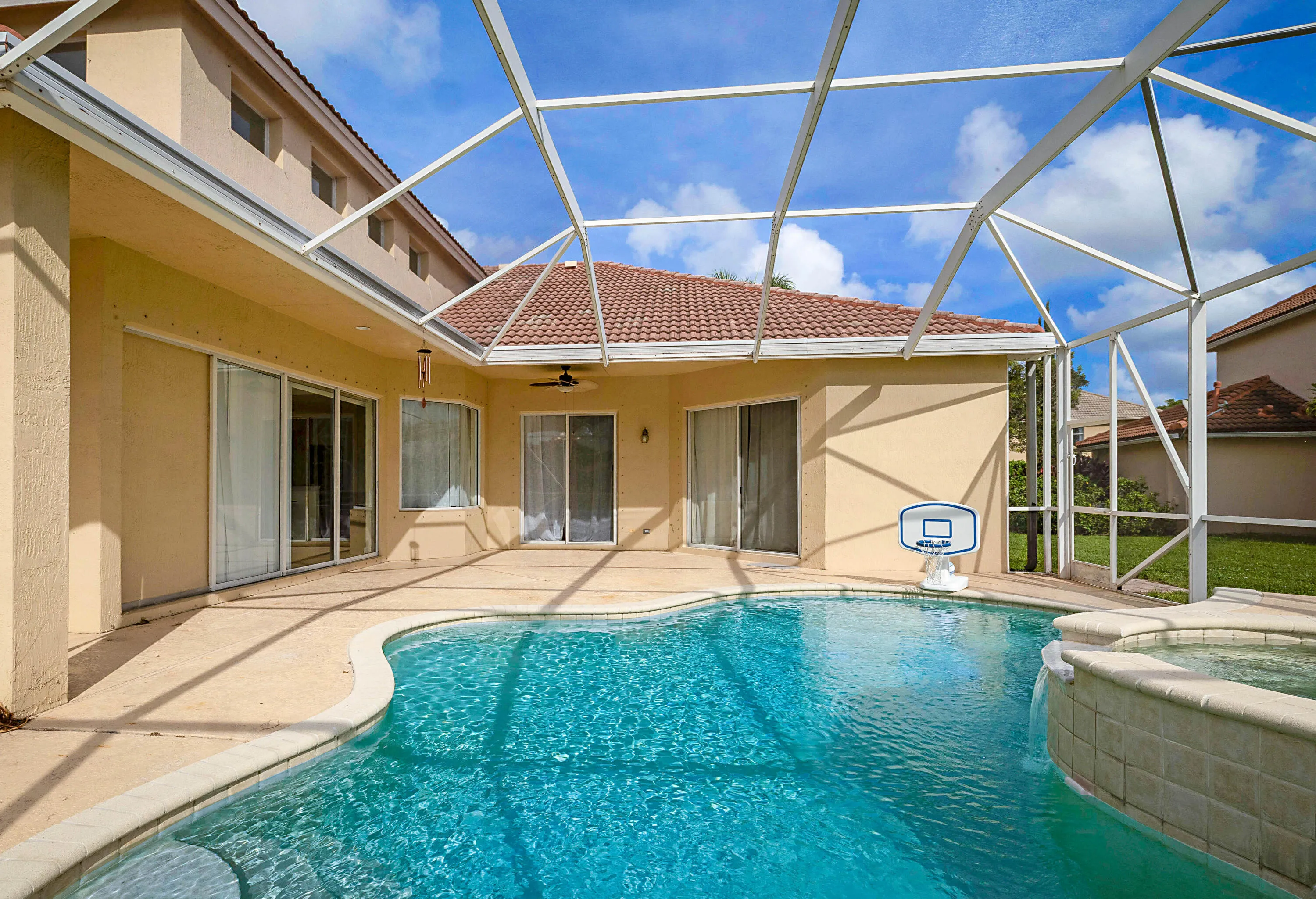 Screened-in outdoor living space with a freeform swimming pool and integrated spa