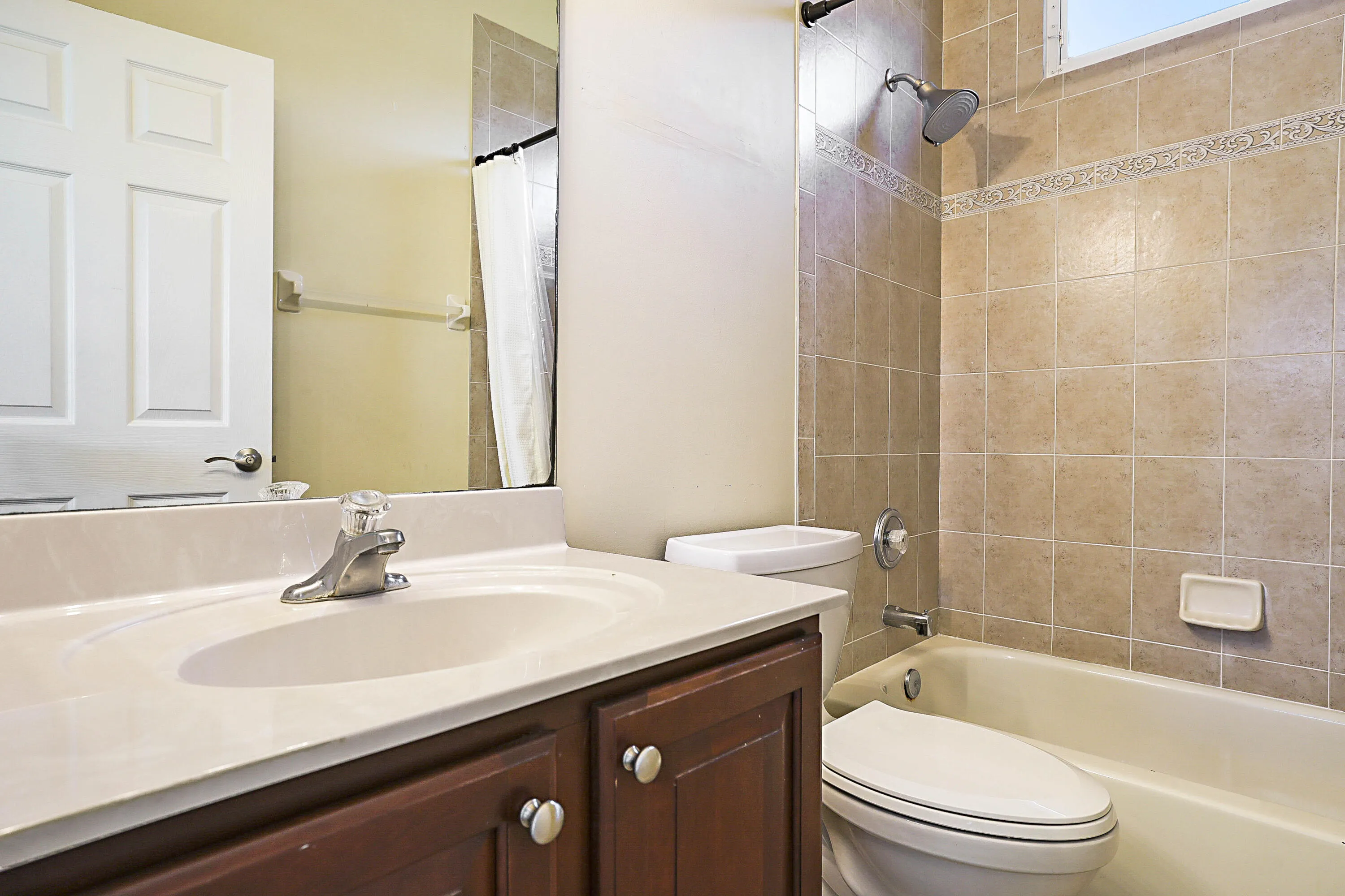 Bathroom featuring a wood-finish vanity with dual-handle faucet, ceramic undermount sink, and white quartz countertop