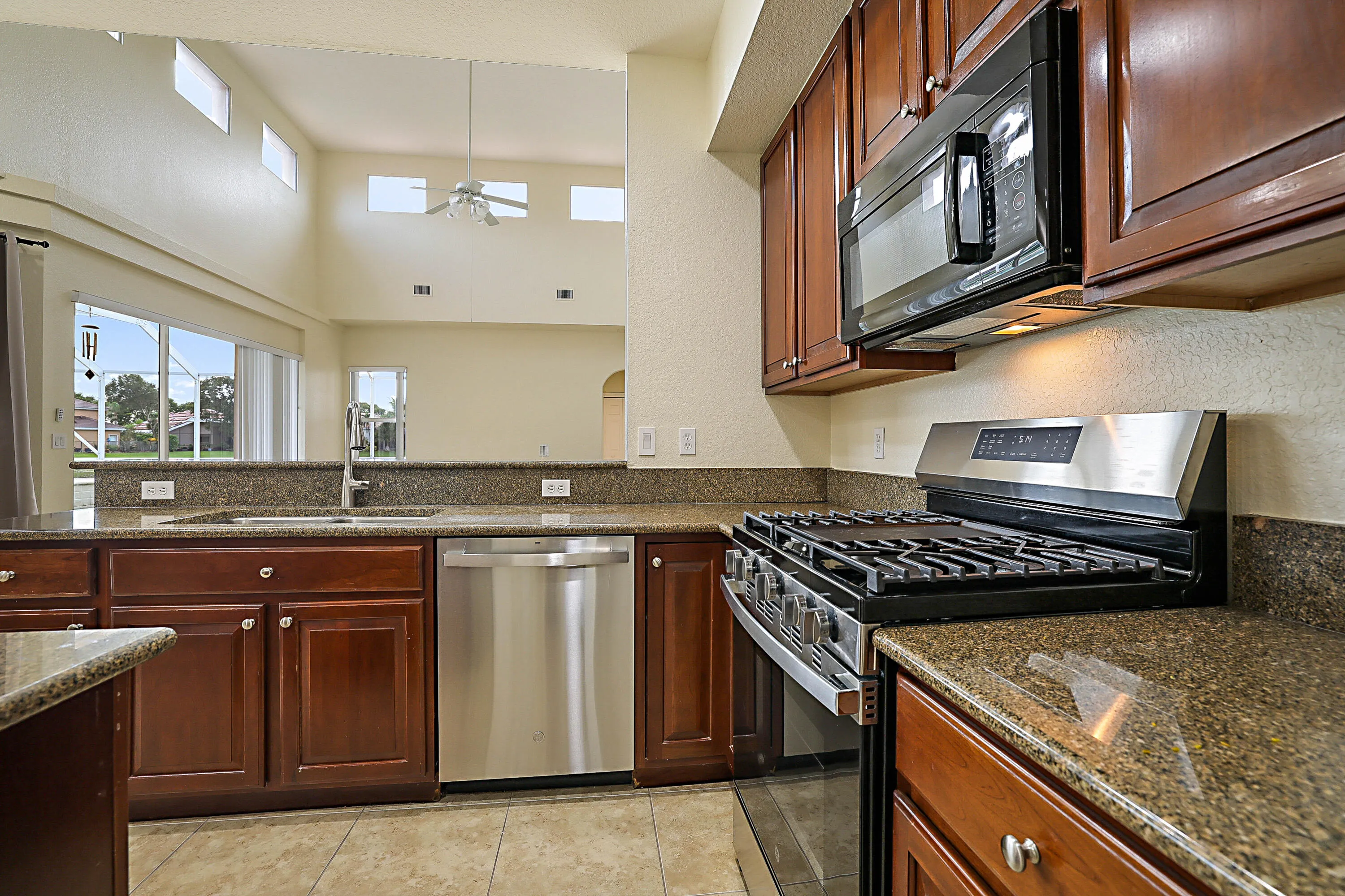 Kitchen featuring wood cabinetry, stainless steel appliances, speckled countertops, and a double basin sink