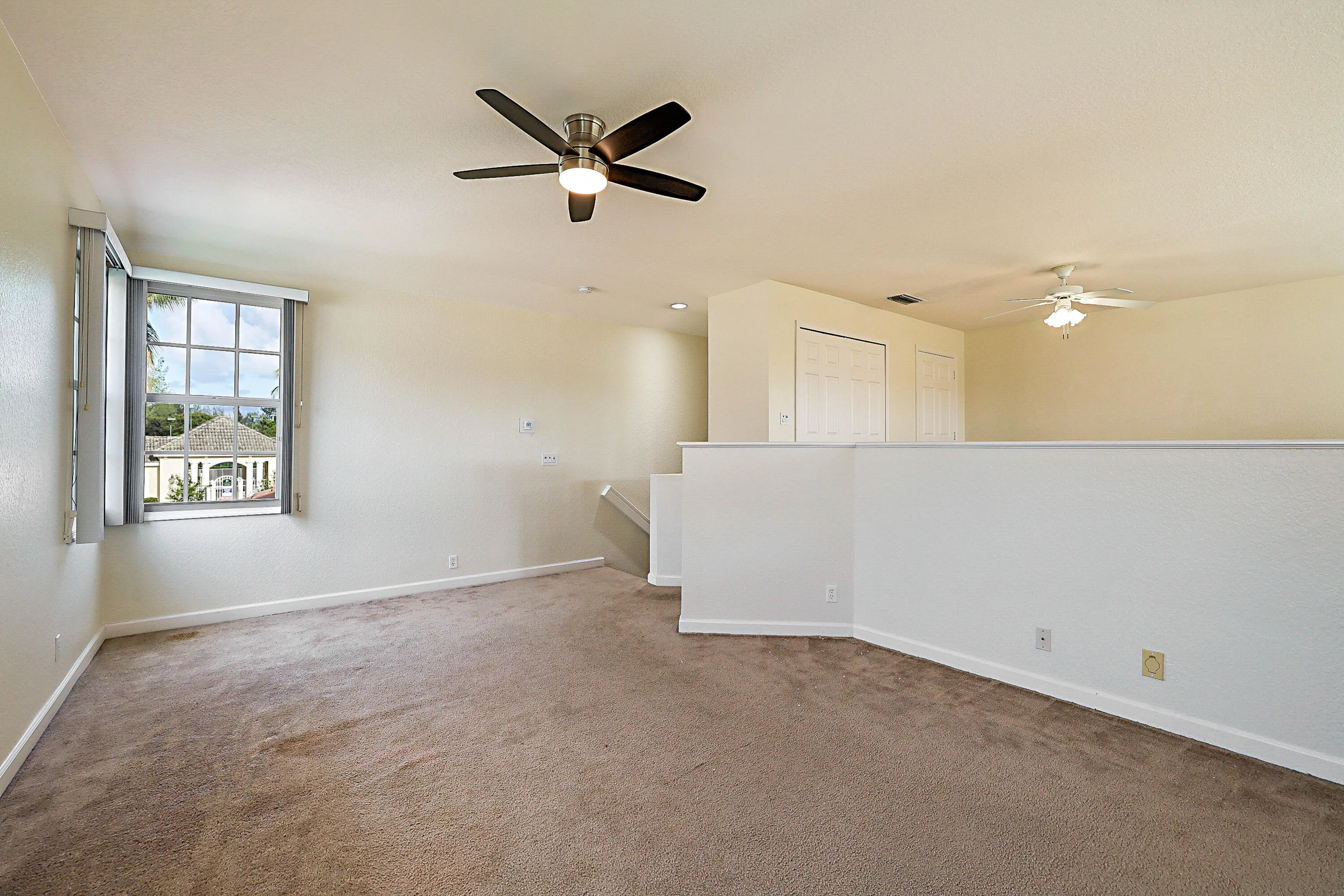 Carpeted interior with two ceiling fans, a multi-pane window, and white interior doors