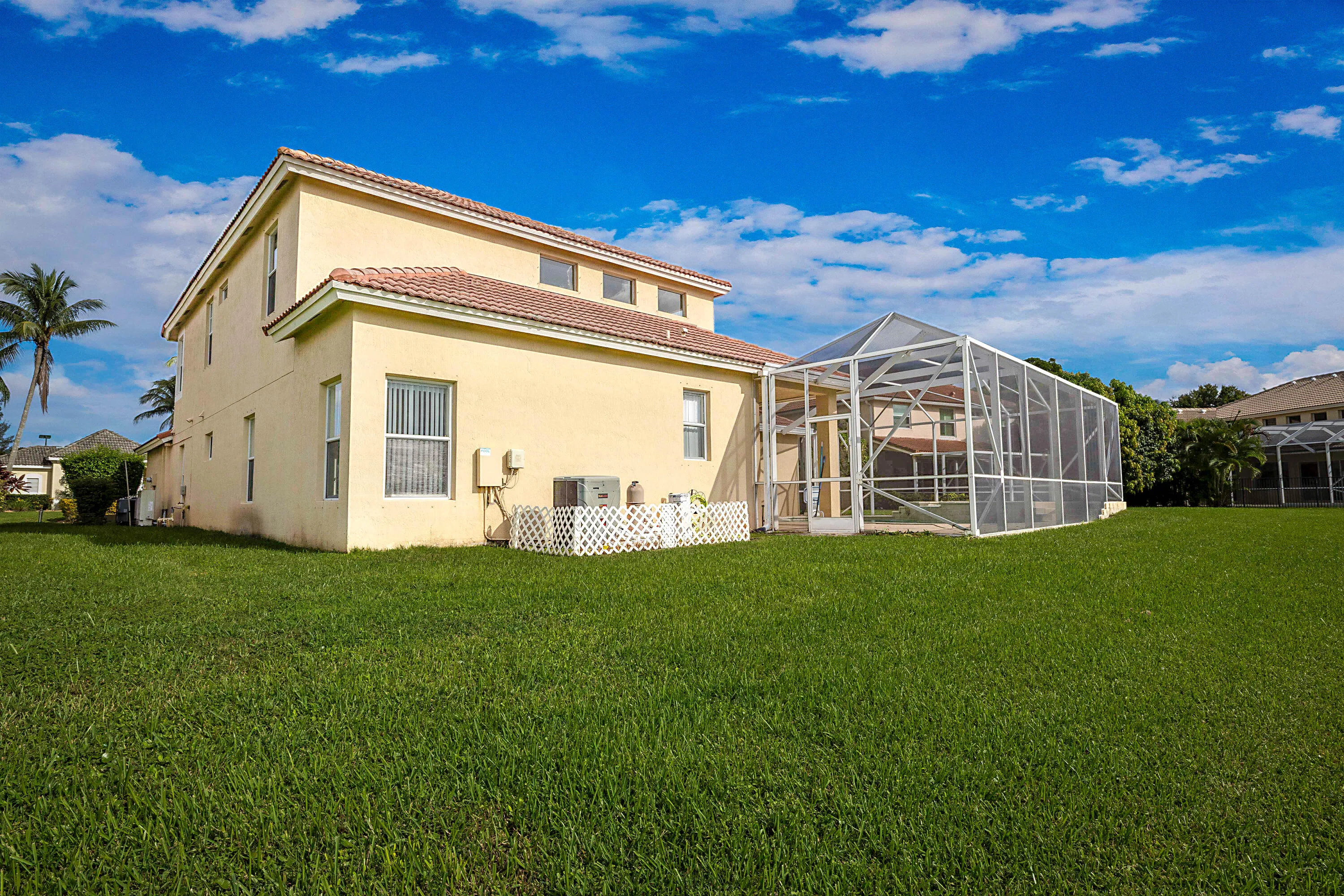 Charming two-story residence with soft yellow exterior and lattice-detailed covered porch