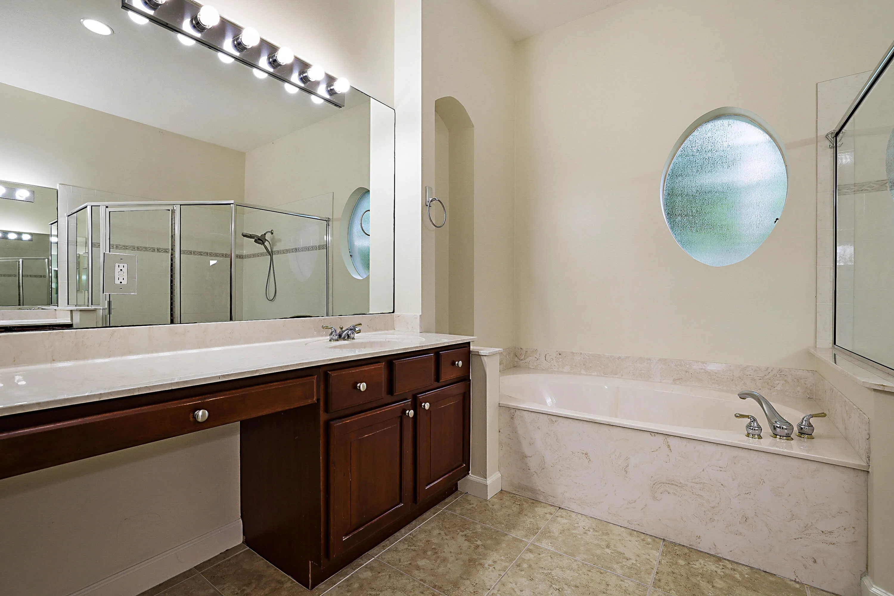 Double vanity with integrated sink, wood-finish cabinetry, and an expansive mirror