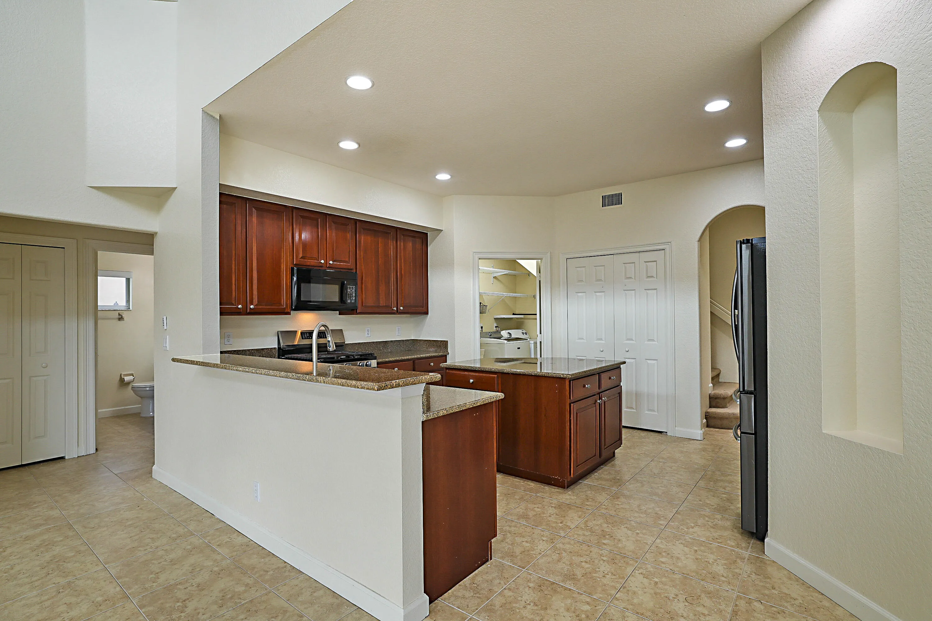 Kitchen featuring recessed lighting, a built-in microwave, wood cabinetry, stone countertops, and tile flooring