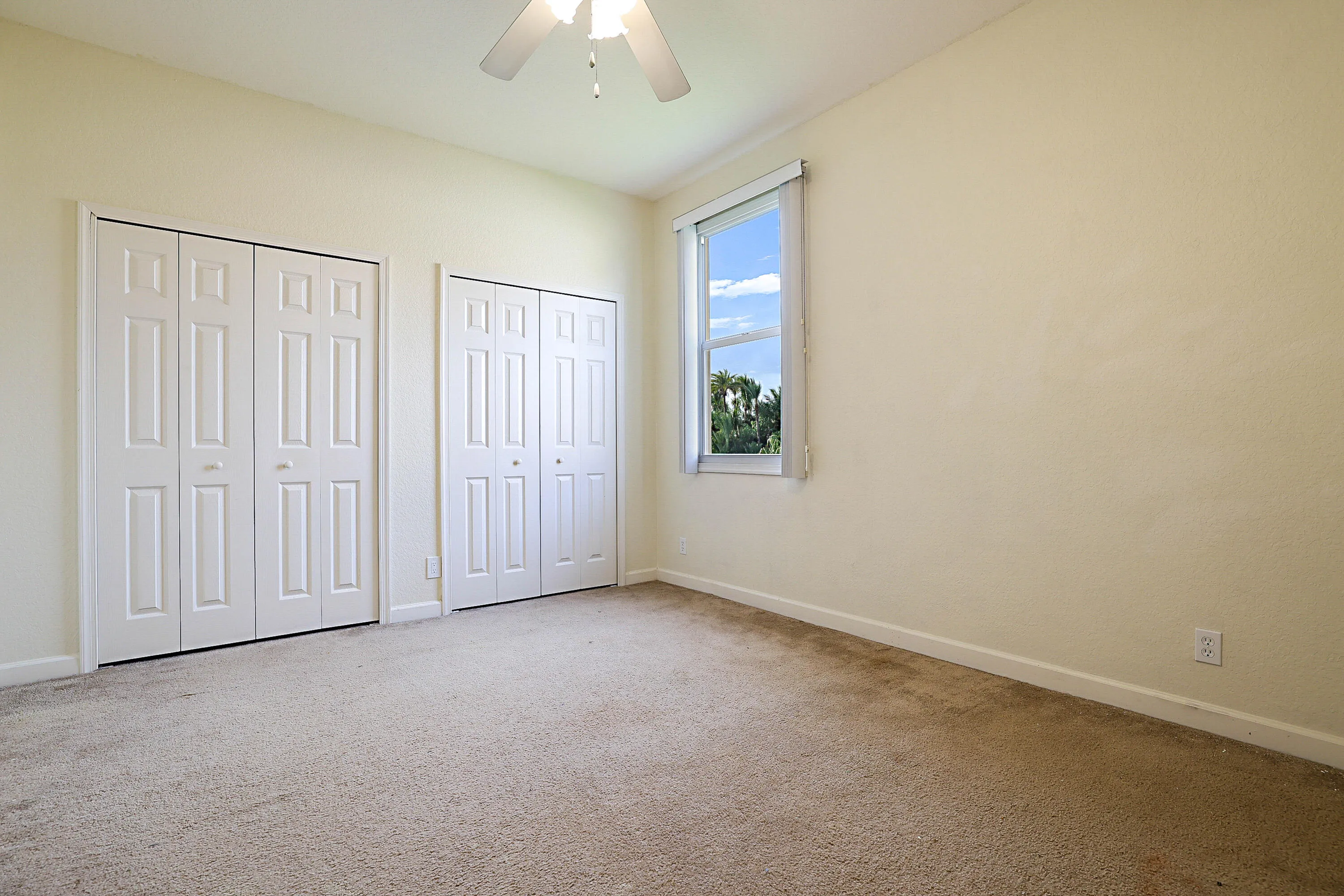 Recessed window, ceiling fan with light, and two sets of bi-fold closet doors