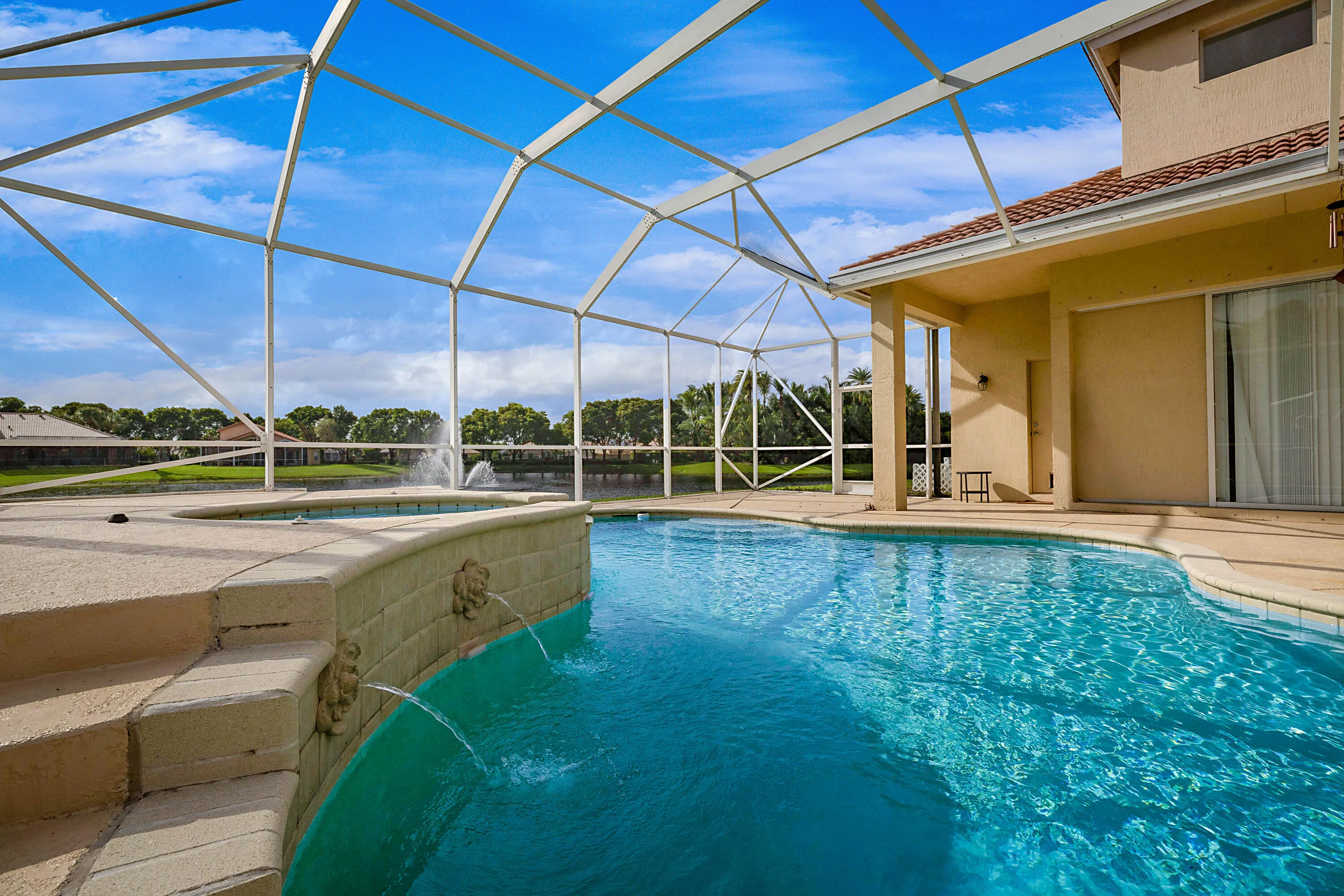 Screened lanai encompassing a curved swimming pool, integrated spa, and an attached covered patio
