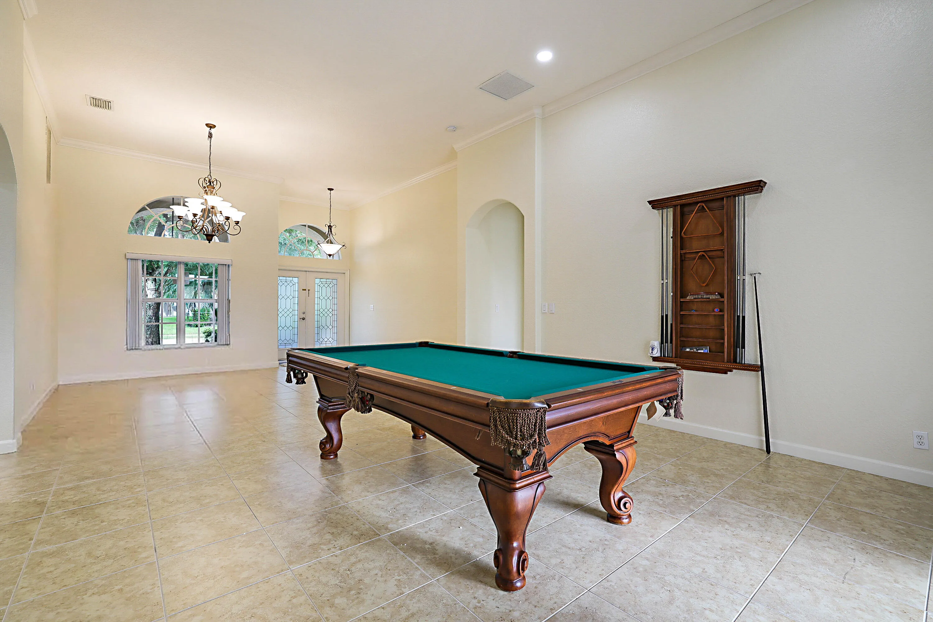 Spacious recreation room featuring polished concrete flooring, recessed ceiling lighting, and decorative pendant fixtures