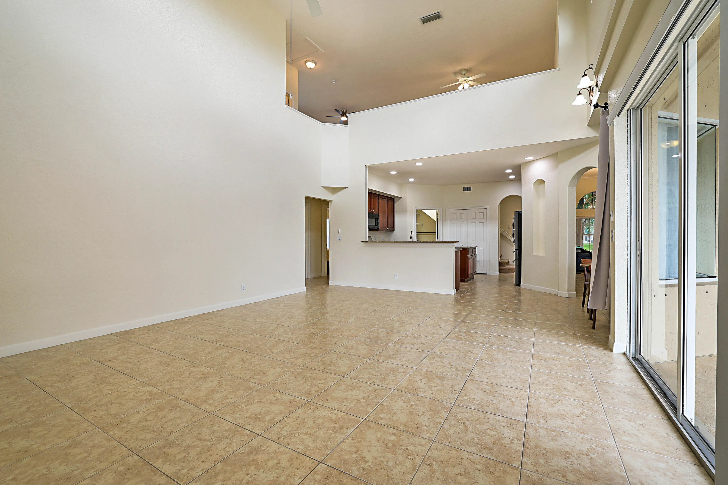 Spacious open-concept living area with soaring vaulted ceilings, recessed lighting, and tile flooring throughout
