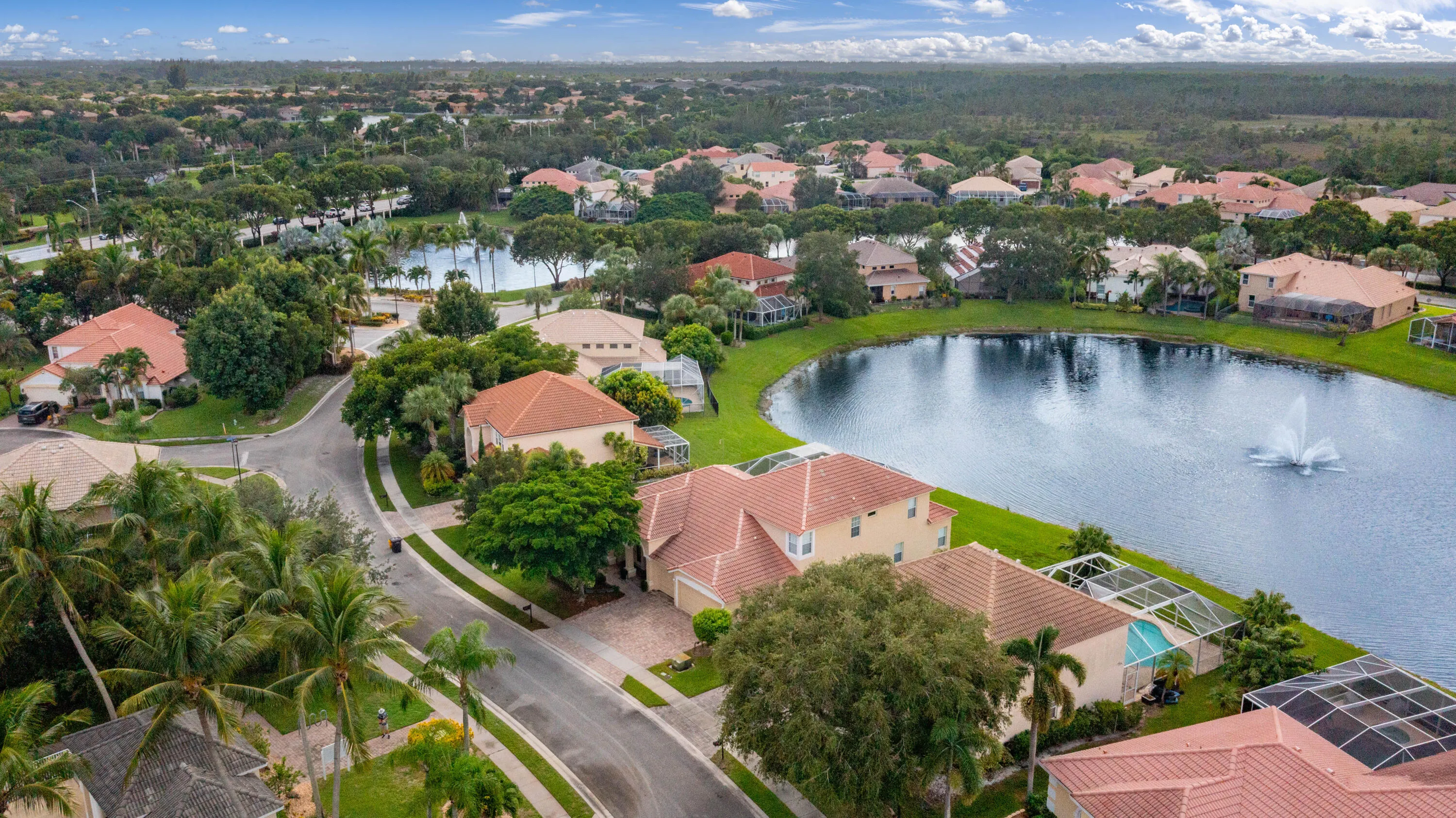 Waterfront estate featuring a lakeside setting with mature landscaping, terracotta tile roof, lush manicured grounds, resort-style pool and spa, and a sprawling residential footprint positioned on premium lakefront acreage within an established community