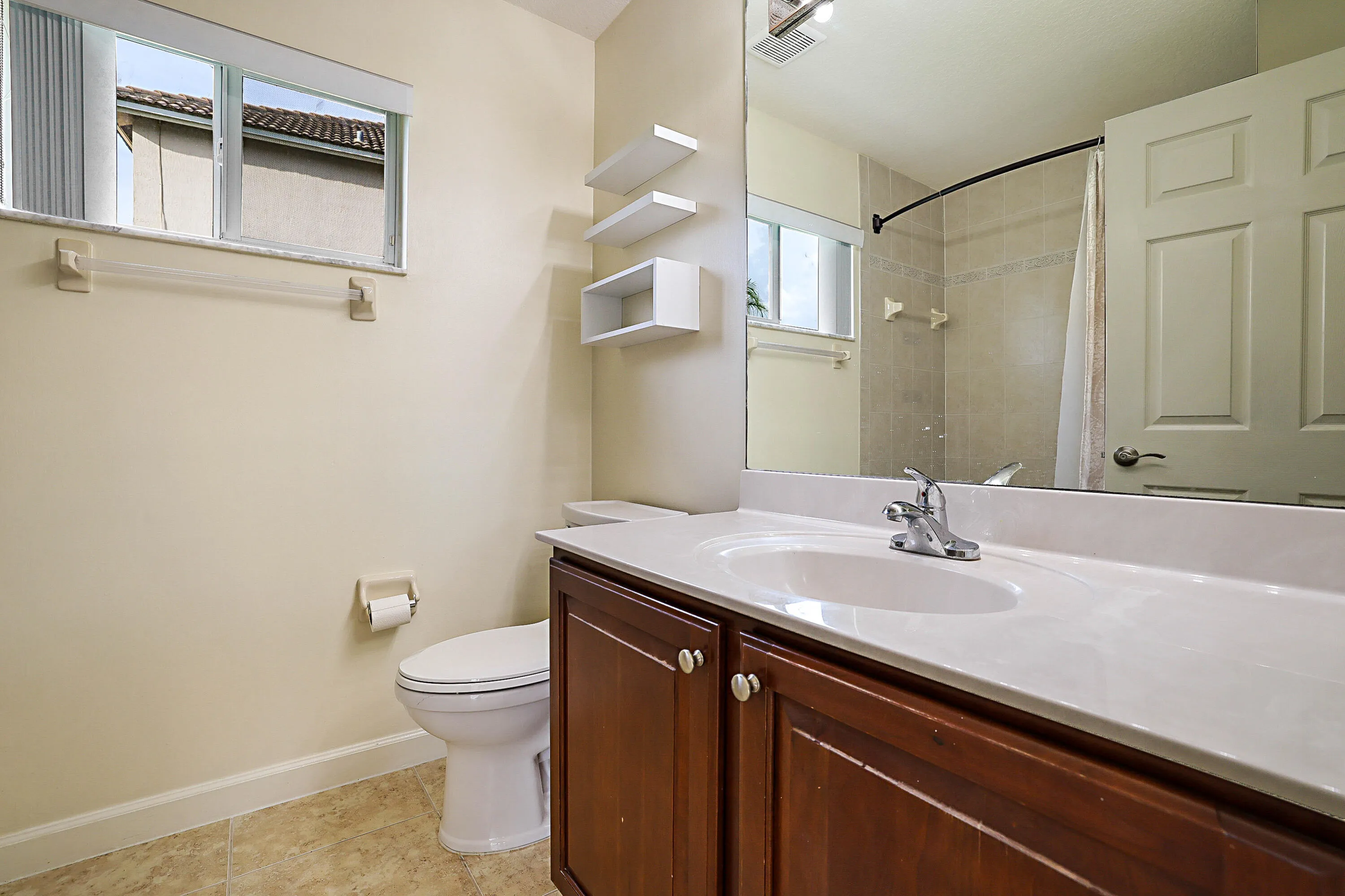 Spa-inspired bathroom featuring a dual-sink vanity with wood-finish cabinetry, white quartz countertop, and chrome faucetry