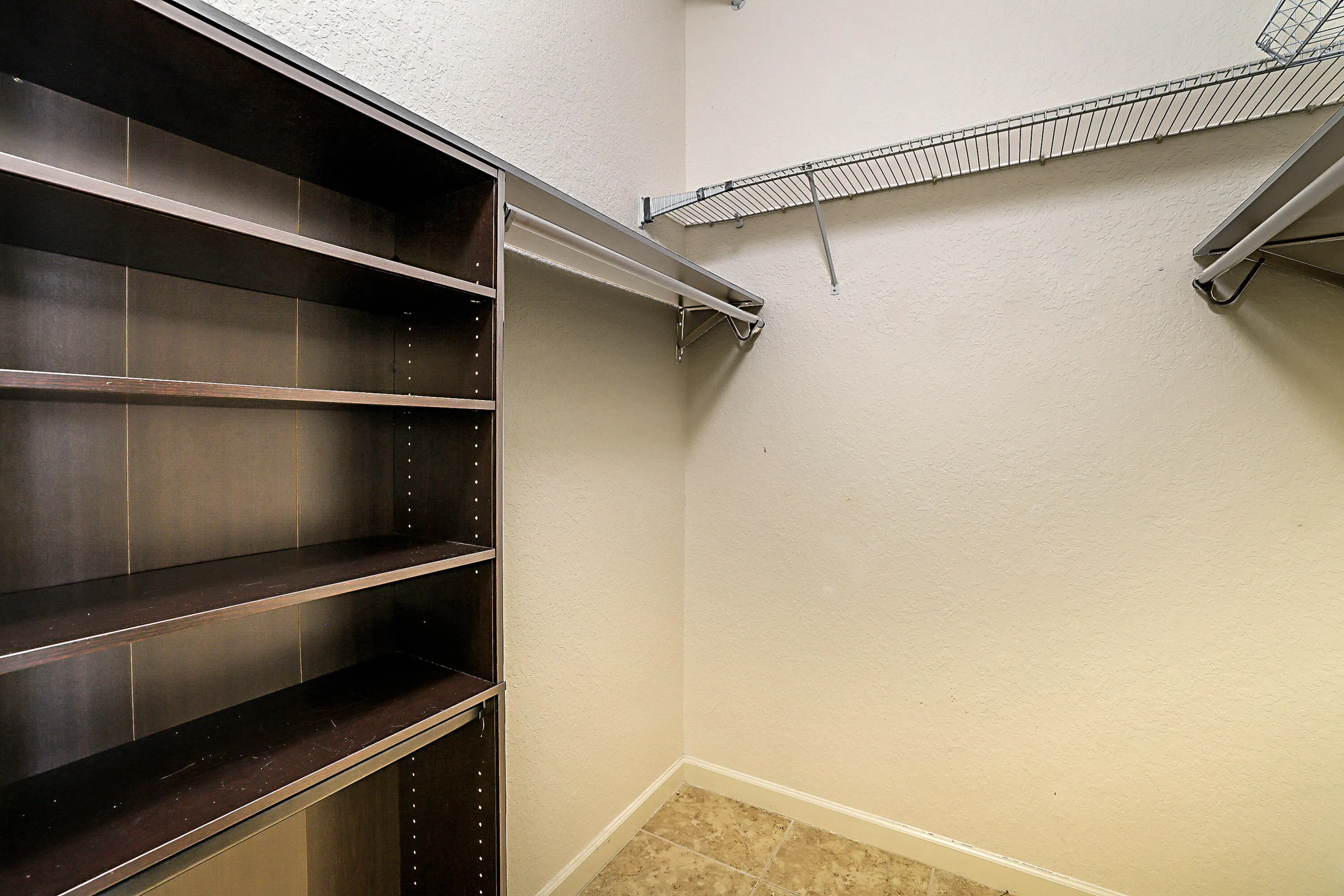 Built-in shelving unit with dark wood-finish, wire shelving, and hanging rods