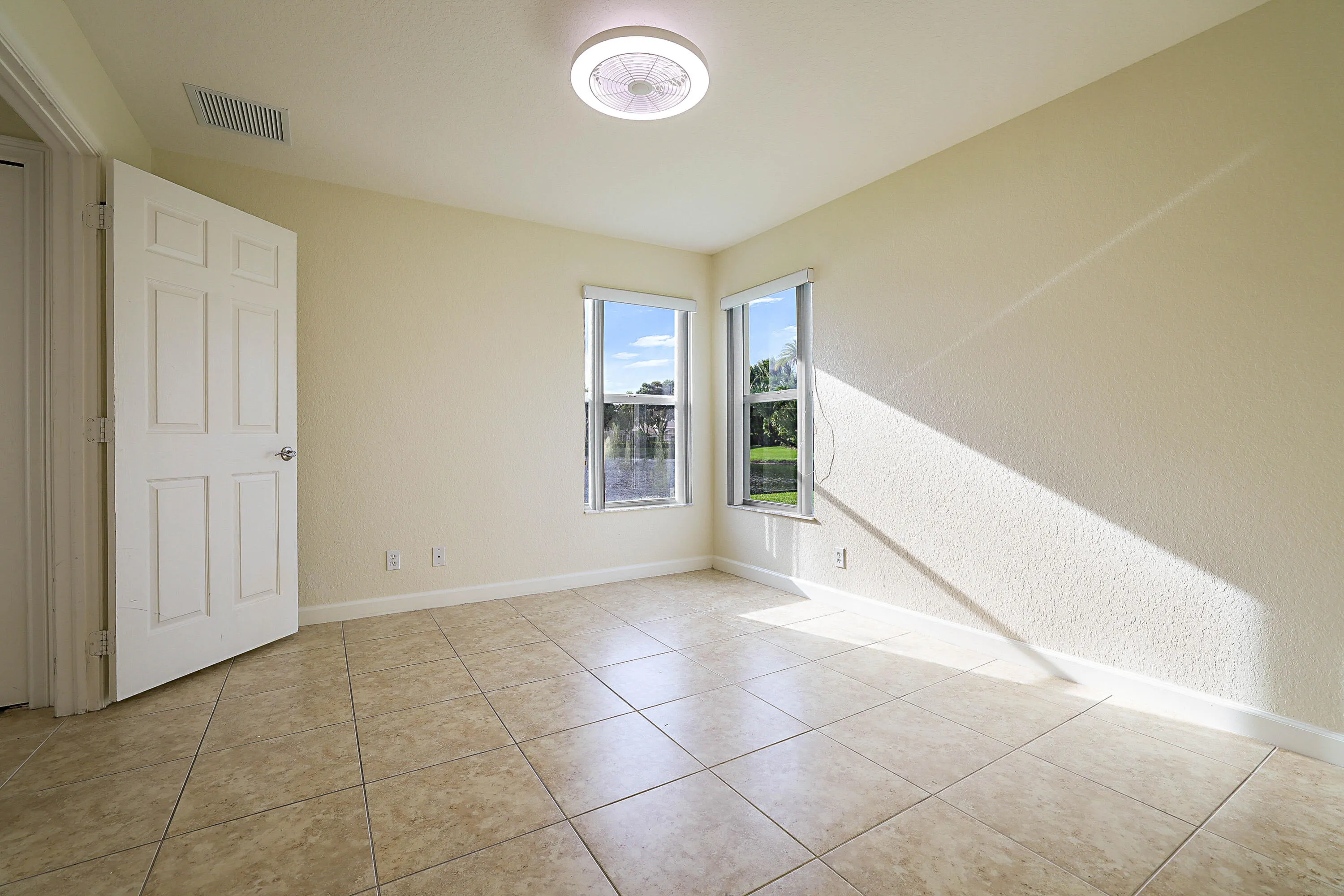 Tiled flooring, two windows, recessed lighting fixture, solid core interior door, and textured walls