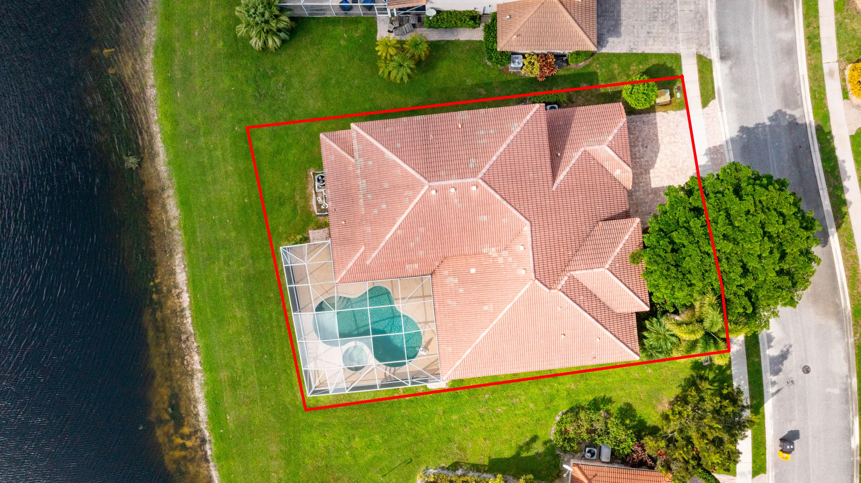 Manicured lawn with mature landscaping, screened-in swimming pool, and tiled roof