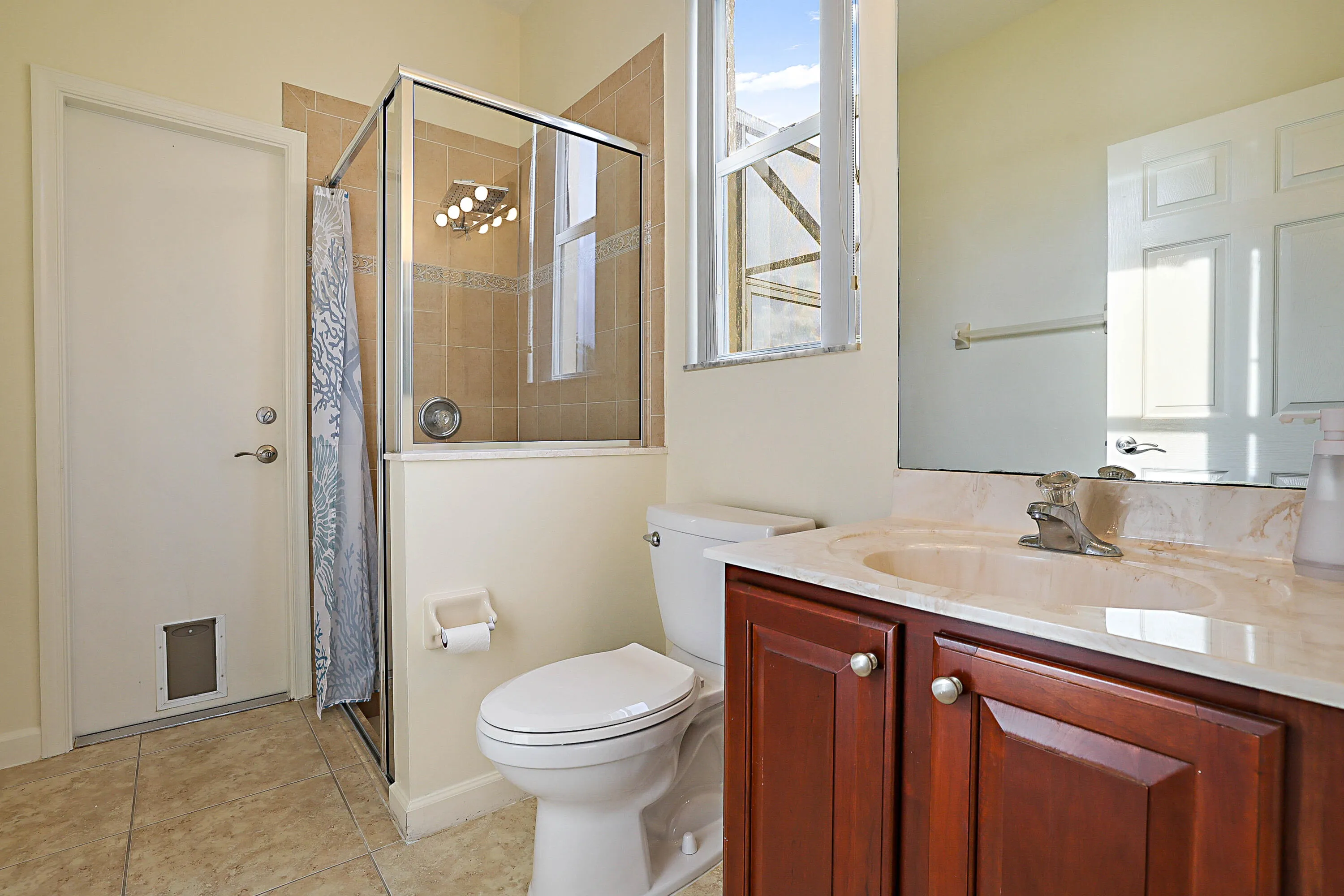Shower enclosure with glass panel, tiled walls, vanity with a light-toned countertop, integrated sink, and wood-finish cabinetry
