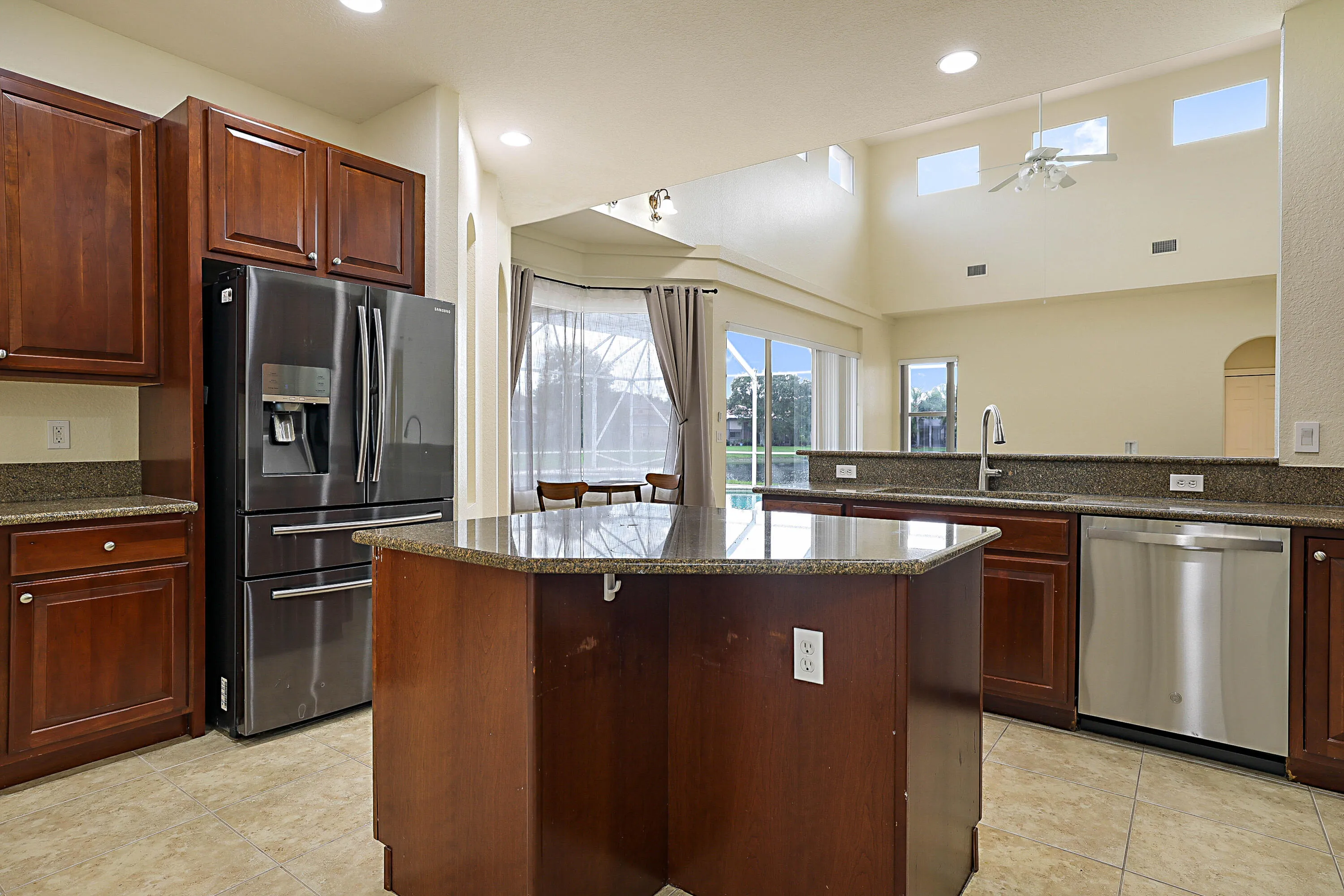 Kitchen featuring wood cabinetry, an island with countertop, stainless steel appliances, and tile flooring