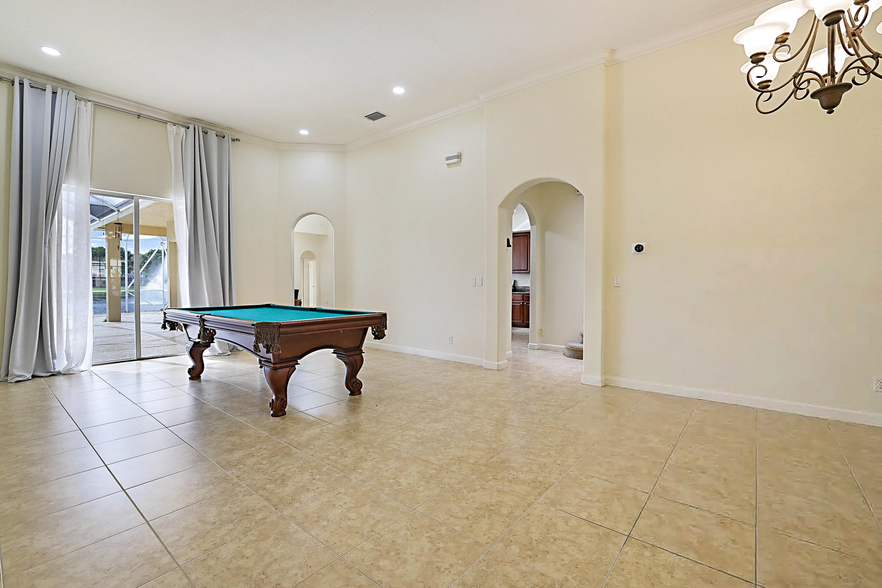 Expansive room featuring tile flooring, crown molding, arched doorways, and recessed lighting