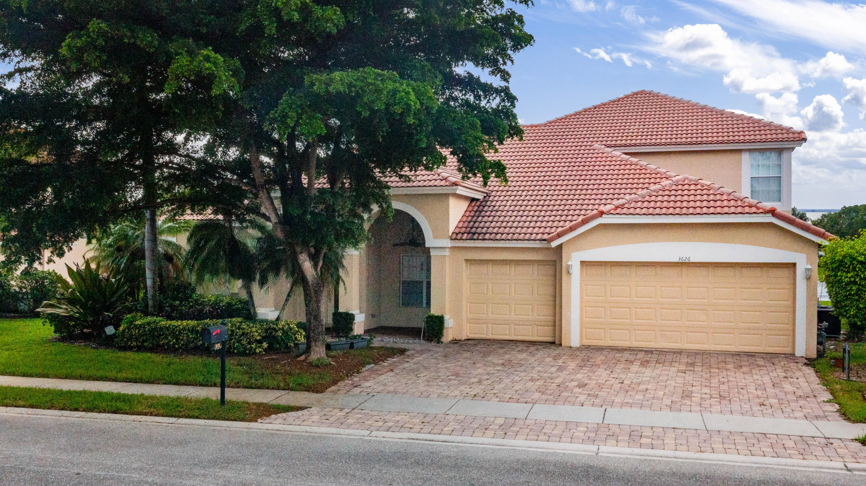 Elegant two-story residence featuring a clay tile hip roof, stucco exterior with arched entryway, and dual three-car garages
