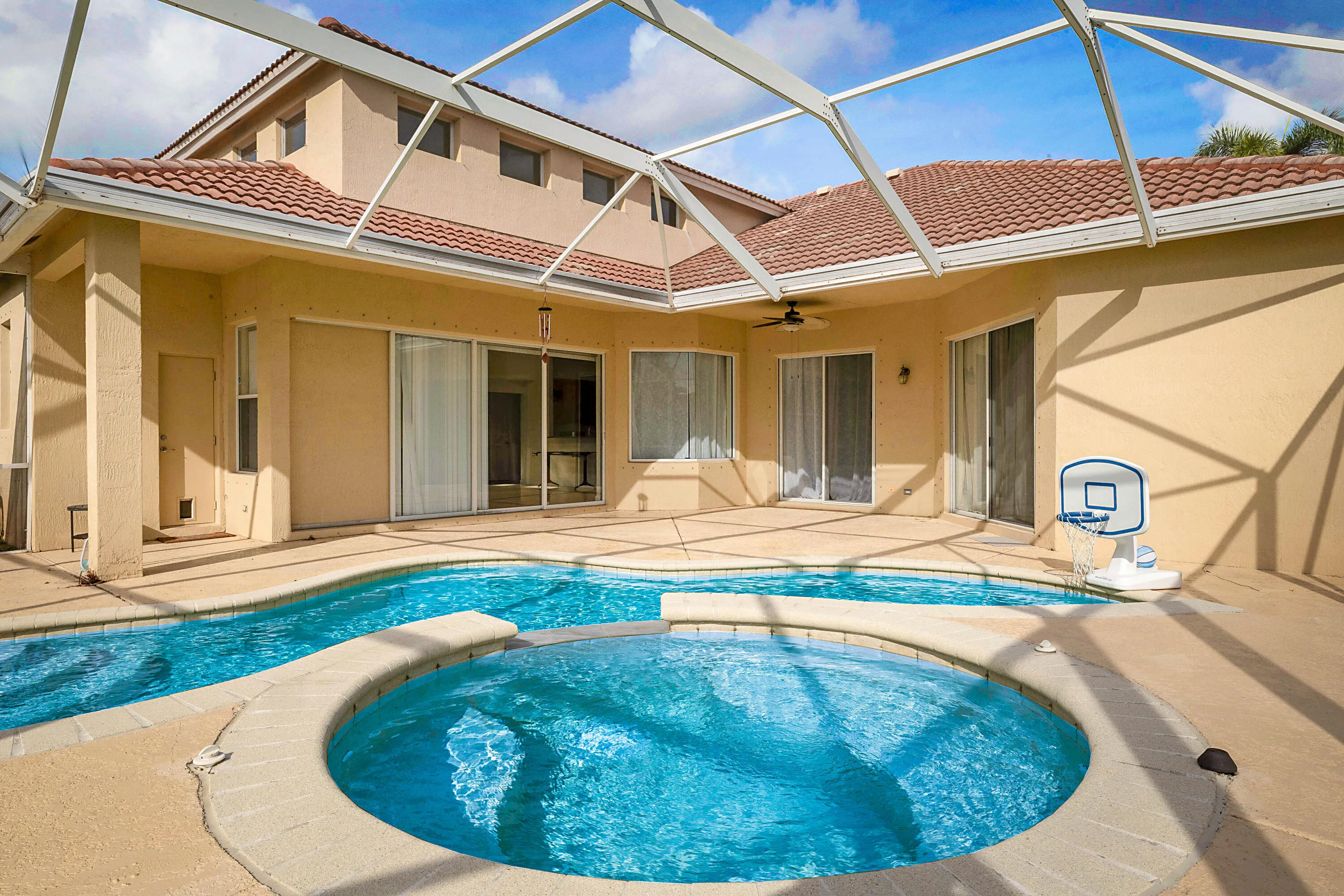 Expansive screened-in lanai with a freeform swimming pool and integrated spa