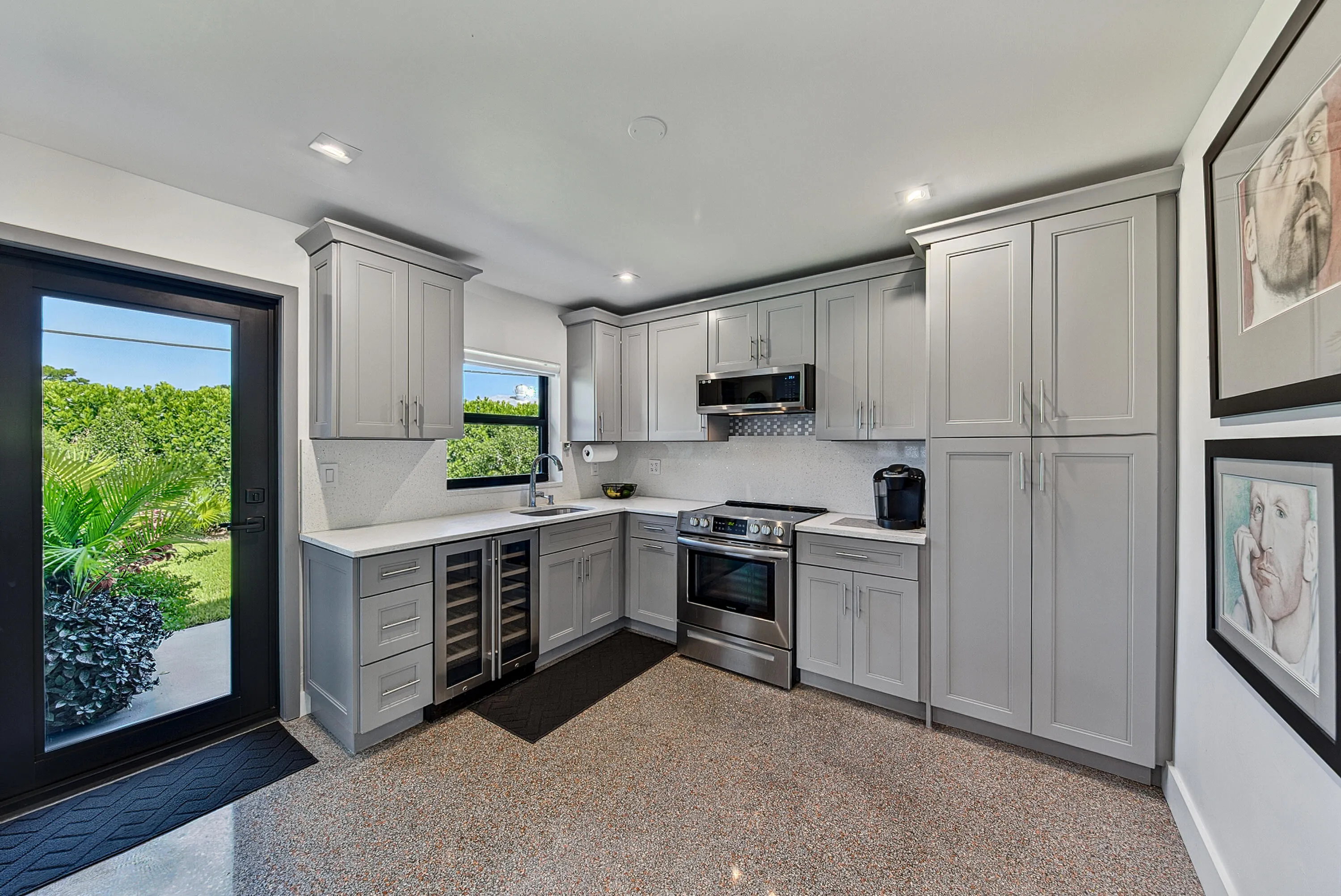Thoughtfully designed kitchen with light gray cabinetry, stainless steel appliances, a built-in wine refrigerator, and quartz countertops.
