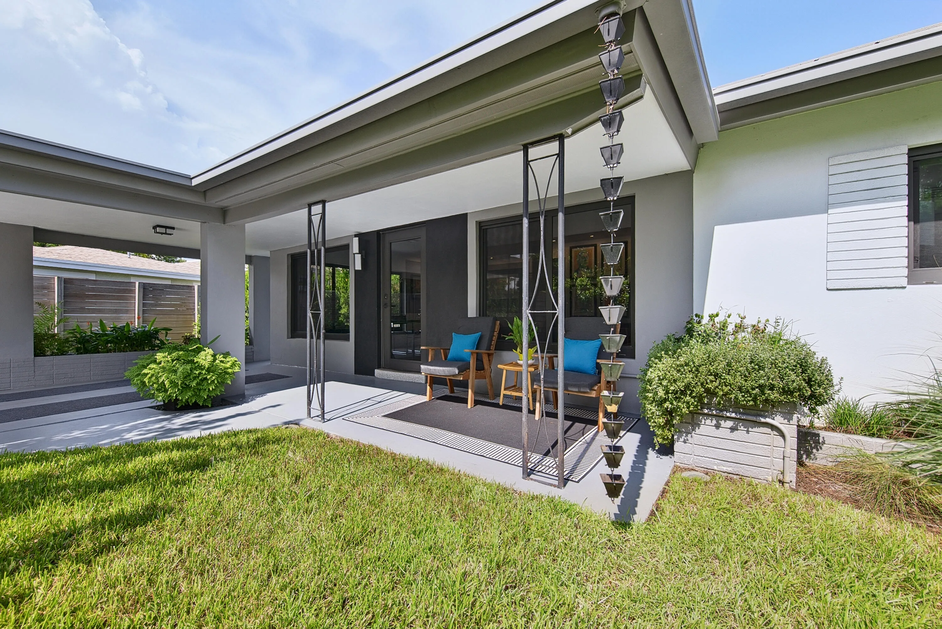 Covered patio surrounded by manicured lawn and established landscaping