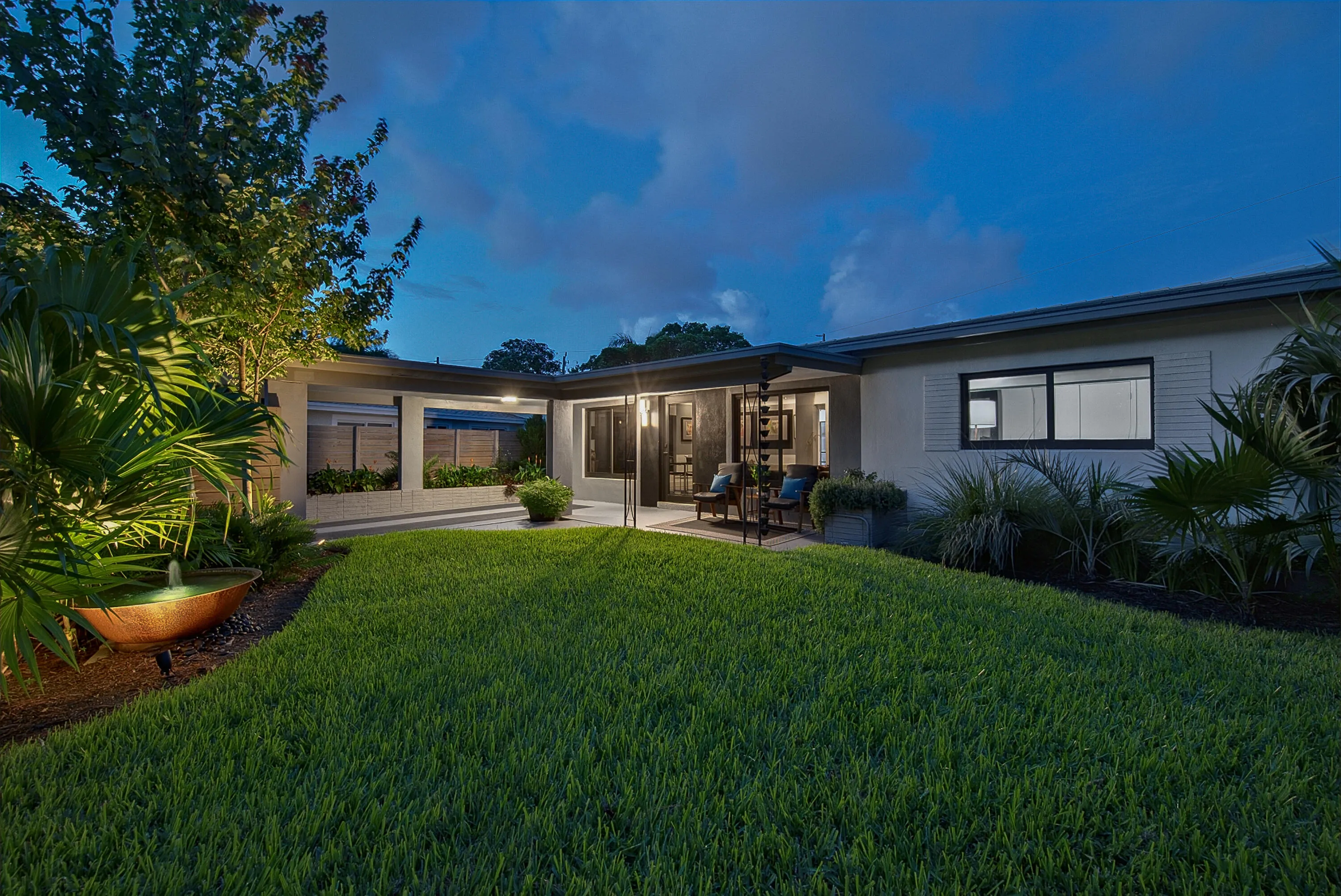 Expansive lawn area, covered patio, integrated planter boxes, modern exterior lighting, and a decorative water feature