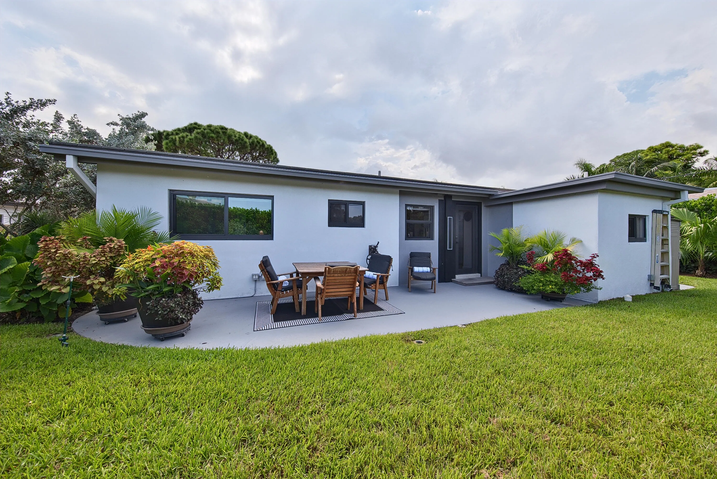 Contemporary exterior with a flat roofline, dark-framed windows, a dark entry door, and a concrete patio