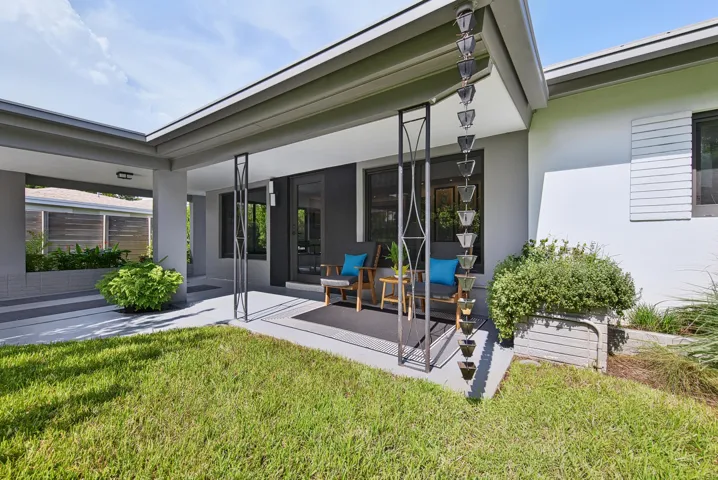 Covered patio surrounded by manicured lawn and established landscaping