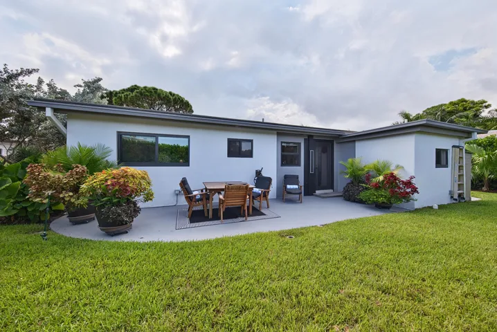 Contemporary exterior with a flat roofline, dark-framed windows, a dark entry door, and a concrete patio