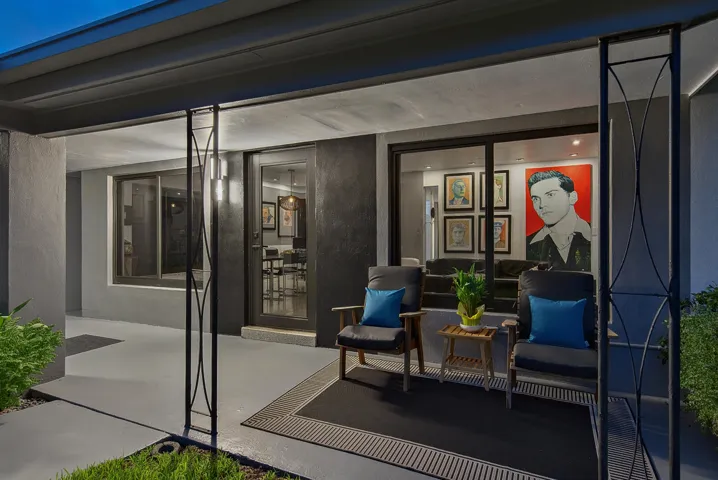 Covered patio with a glass-paneled entry door and wall of windows brings the outside in day and night