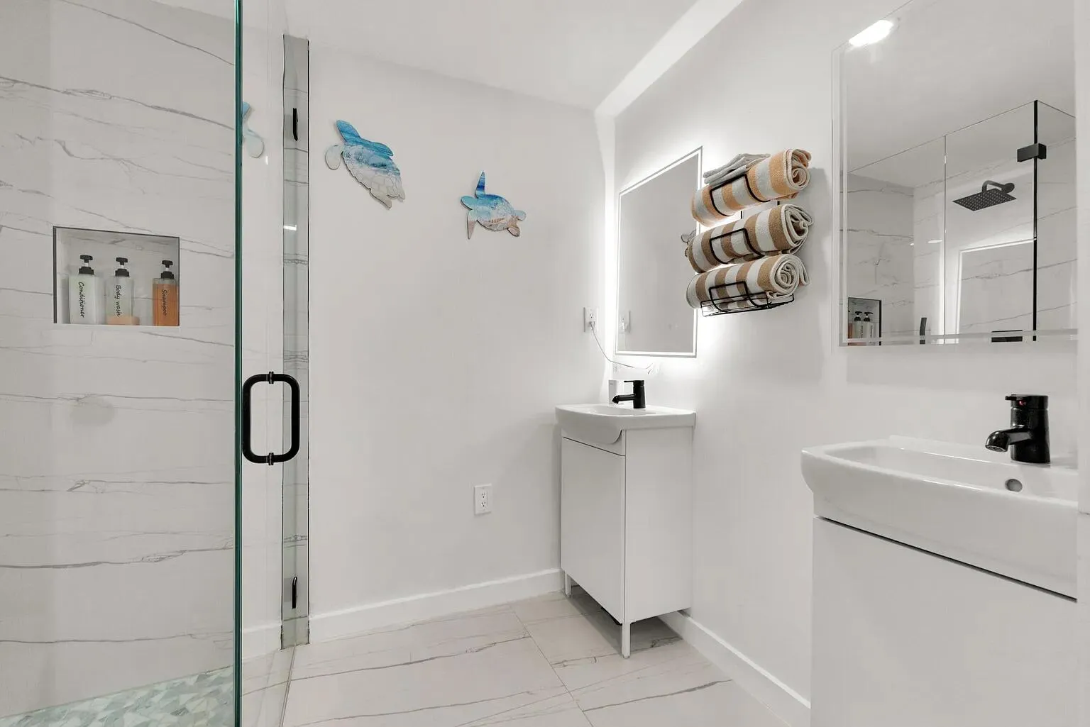 Walk-in shower with clear glass enclosure, integrated shower niche, and white tile surround