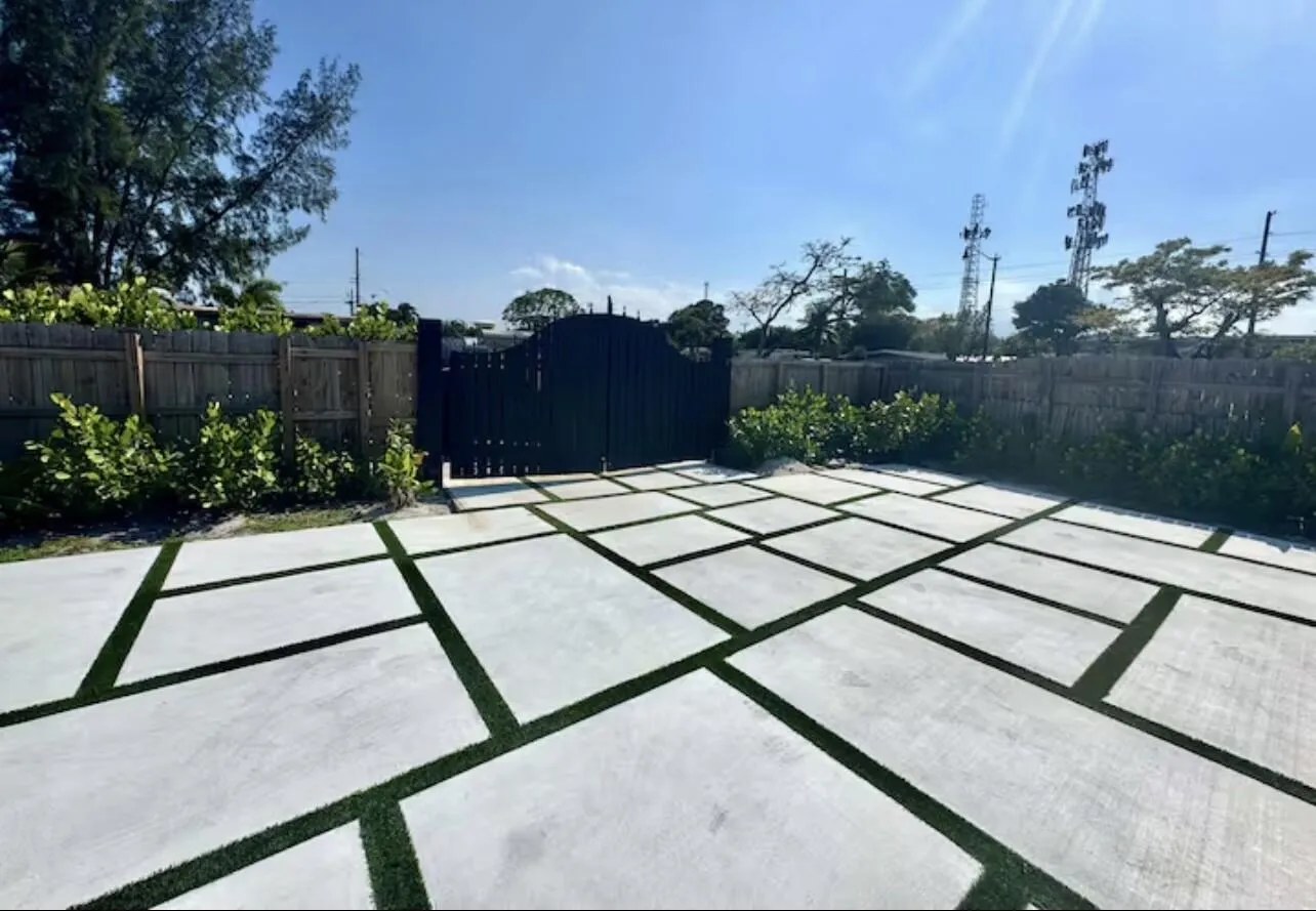 Expansive paved area featuring geometric concrete pavers and artificial turf accents