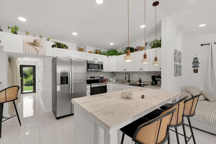 White shaker cabinetry, stainless steel appliances, a wood-finish island countertop, recessed lighting, and pendant lighting fixtures