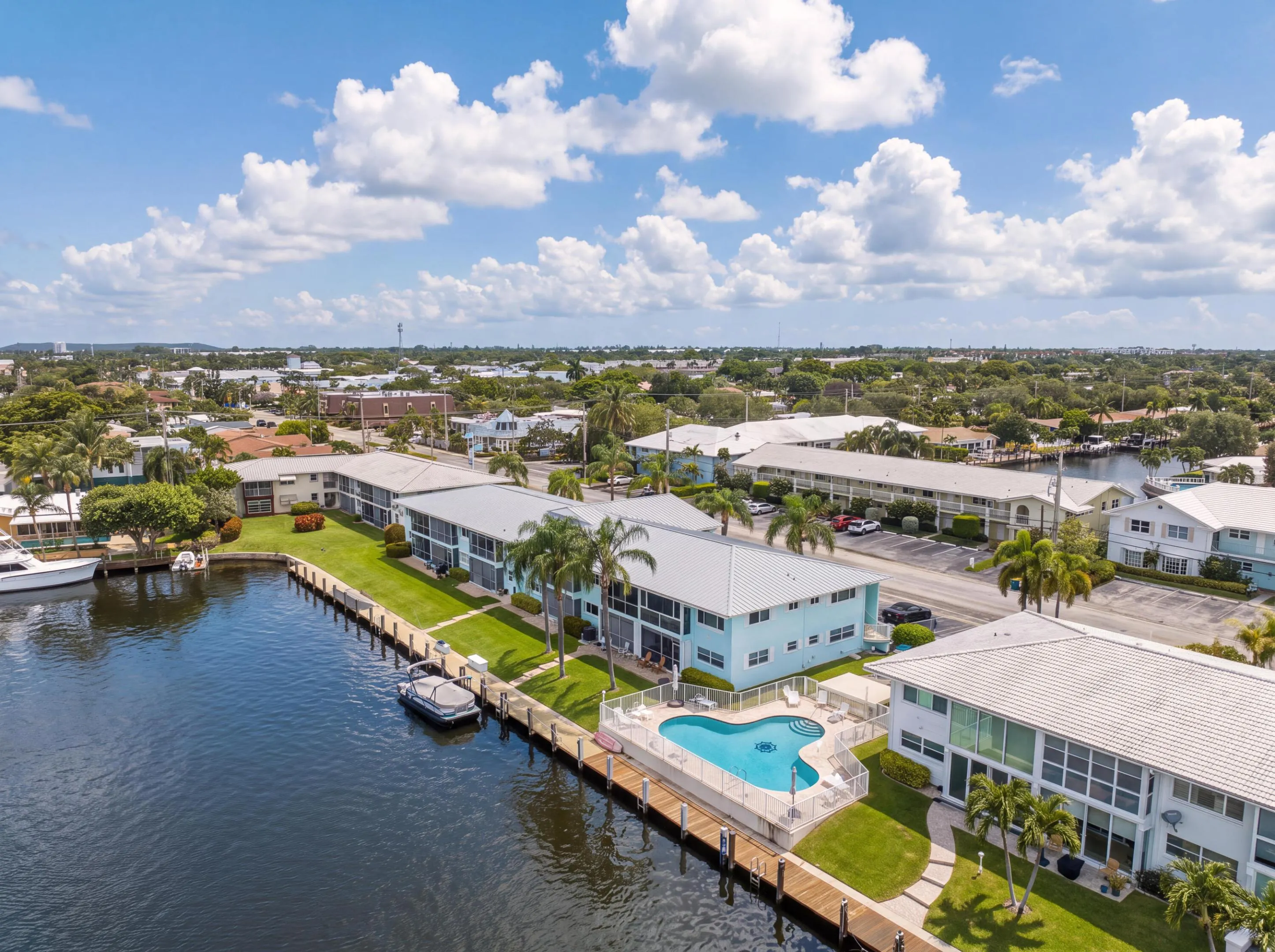 Waterfront property with private boat docks, a swimming pool, and mature palm trees
