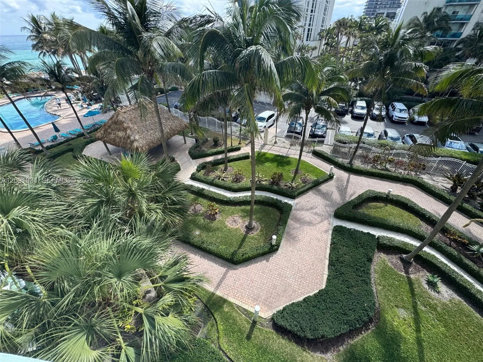 Pool area, beach access with Tiki Hut and lush landscaping.