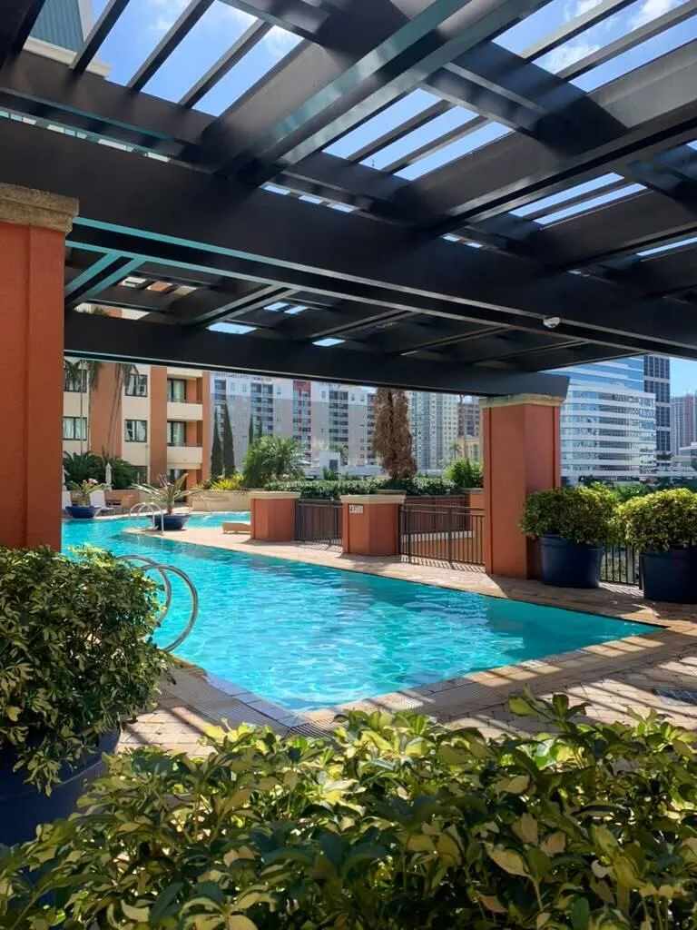 Swimming pool with integrated steps, surrounded by paver decking and mature landscaping