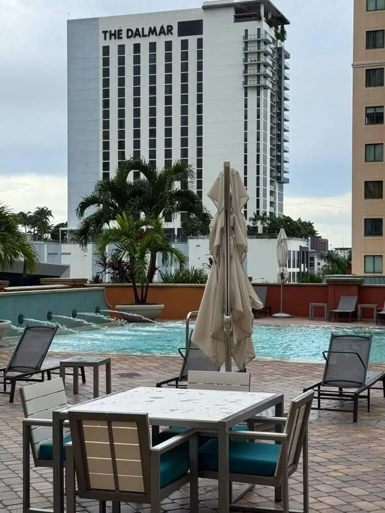 Pool deck featuring brick paving, a swimming pool with water features, and lounge seating