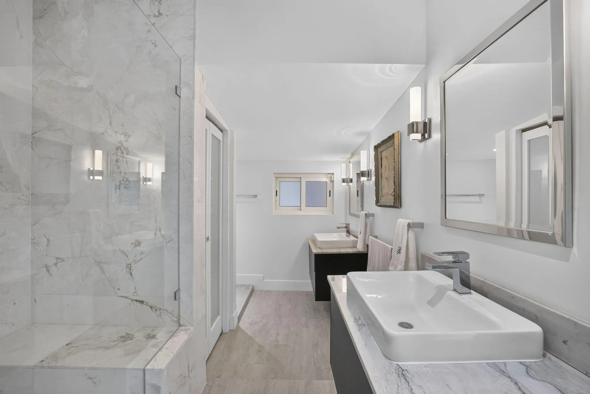 Glass-enclosed shower with a built-in bench, dual rectangular vessel sinks, and tile flooring