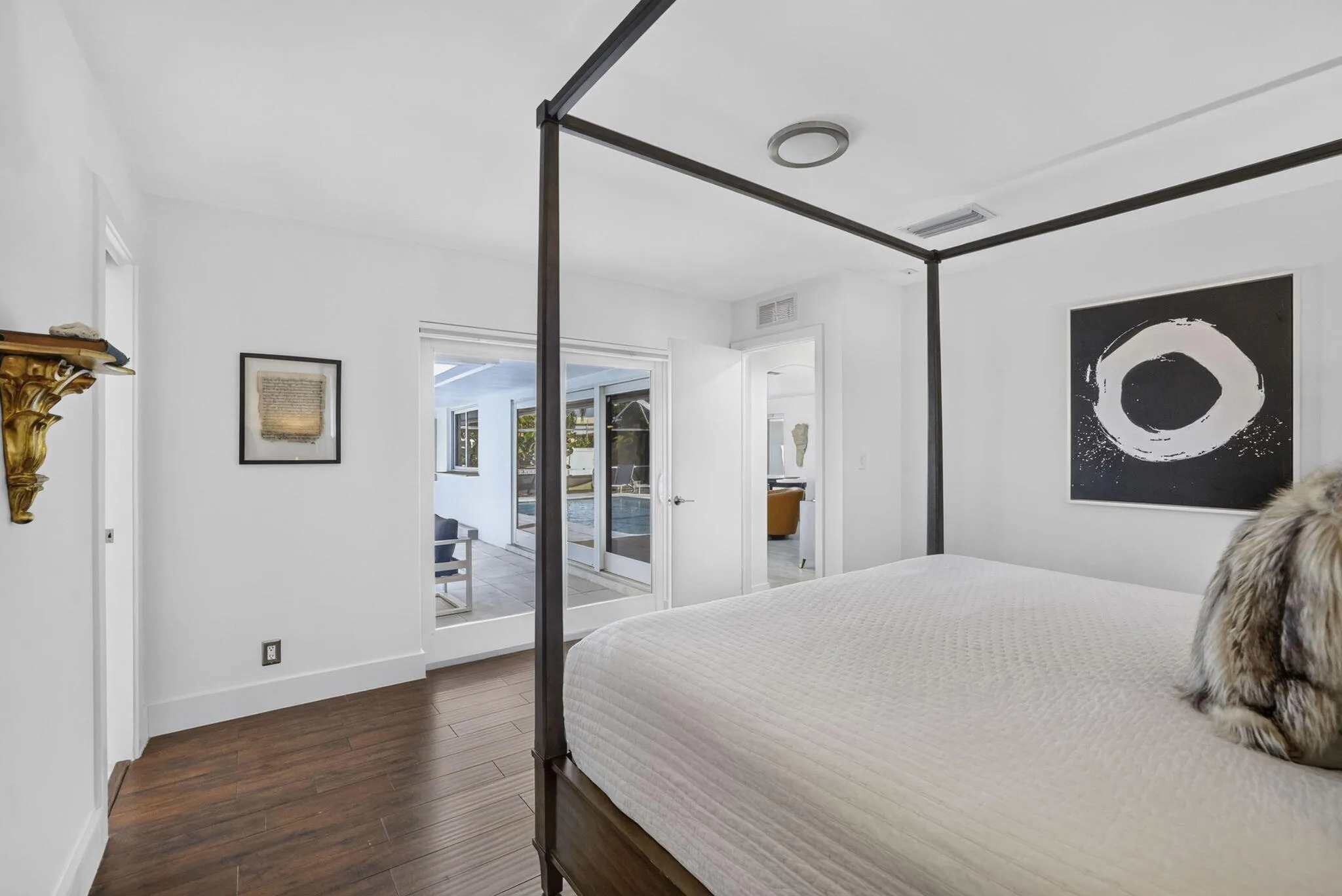 Wood-finish flooring, white walls, recessed ceiling lighting, and a doorway opening to an exterior patio