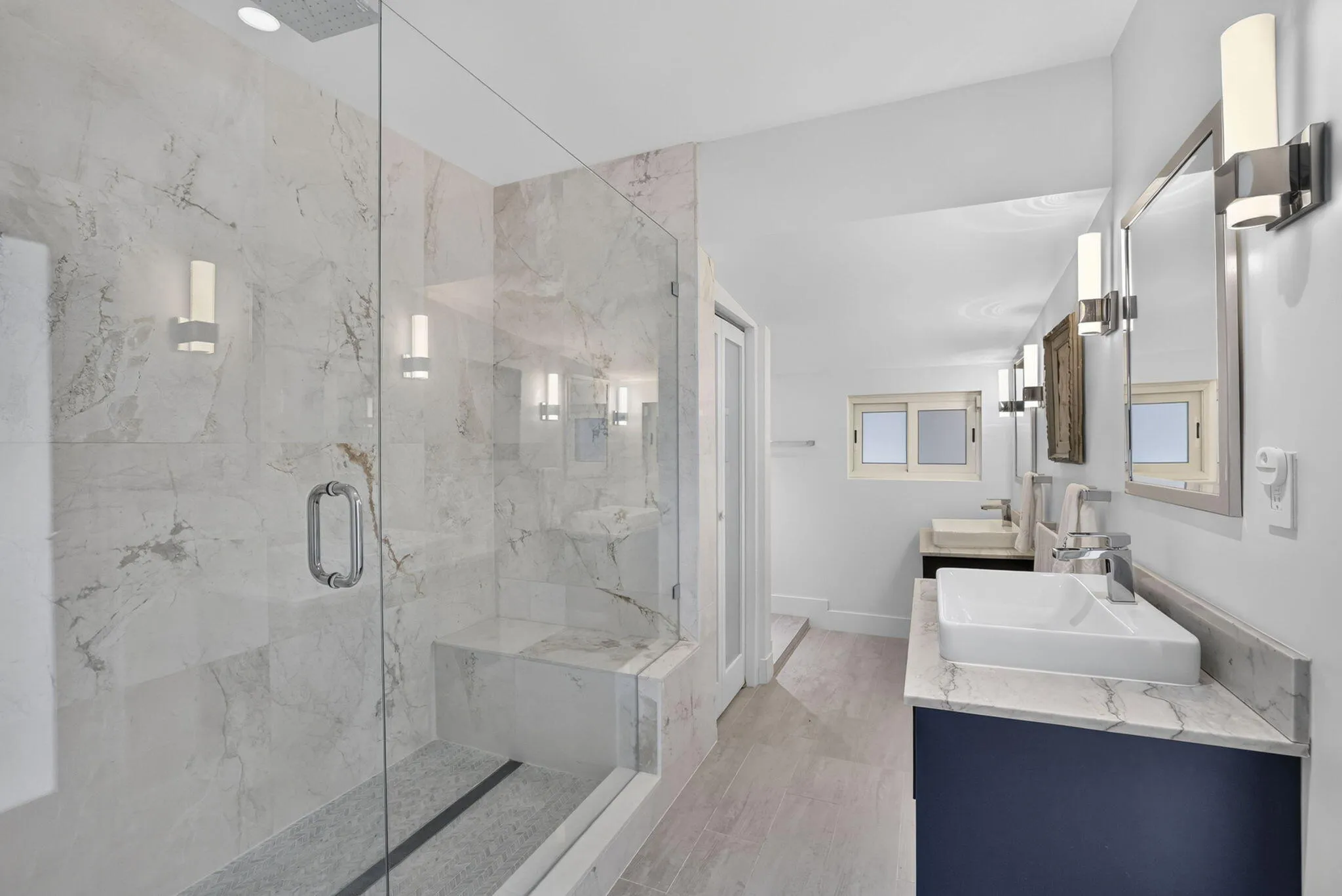 Glass-enclosed shower with a built-in bench and large format tile surround