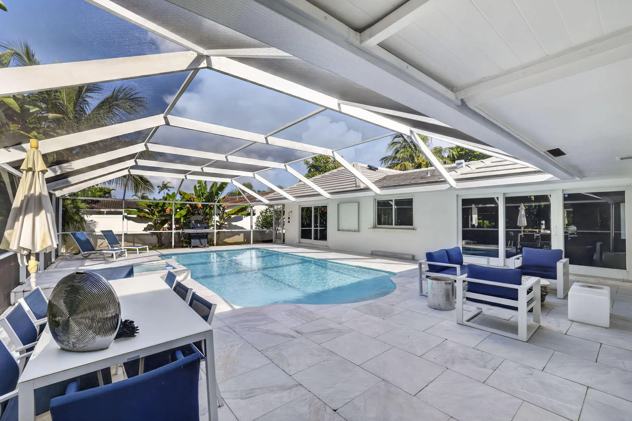 Screened outdoor living area featuring a swimming pool, spacious tiled patio, and covered dining area