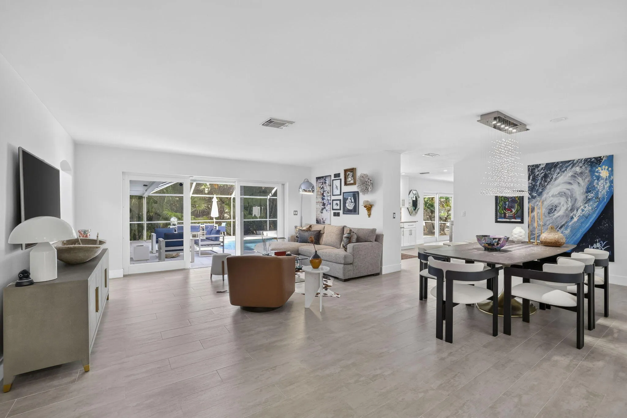 Open-concept living space featuring light-toned tile flooring, recessed lighting, and expansive glass sliding doors