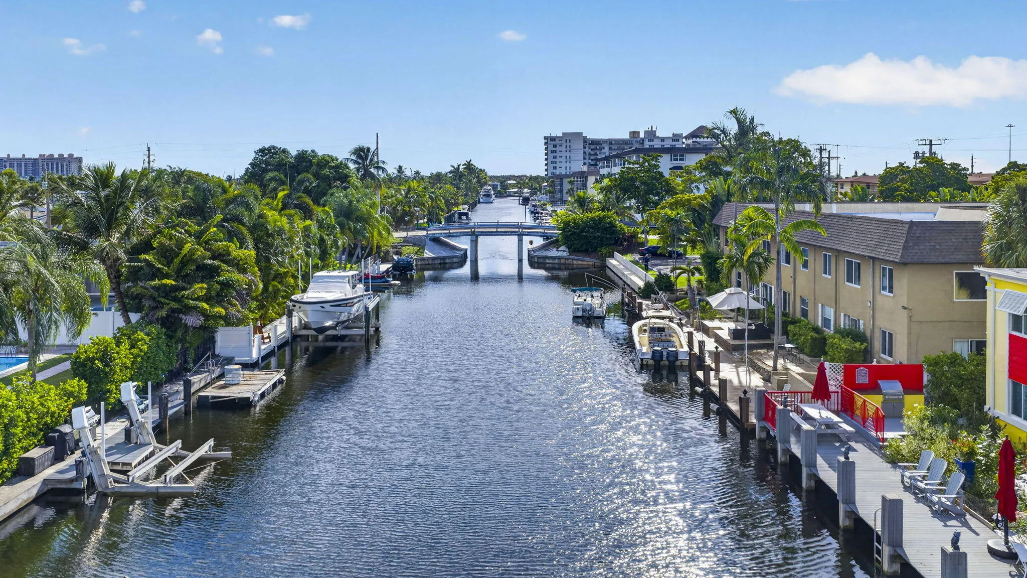 Waterfront property featuring multiple boat docks, mature tropical landscaping, and a canal bridge