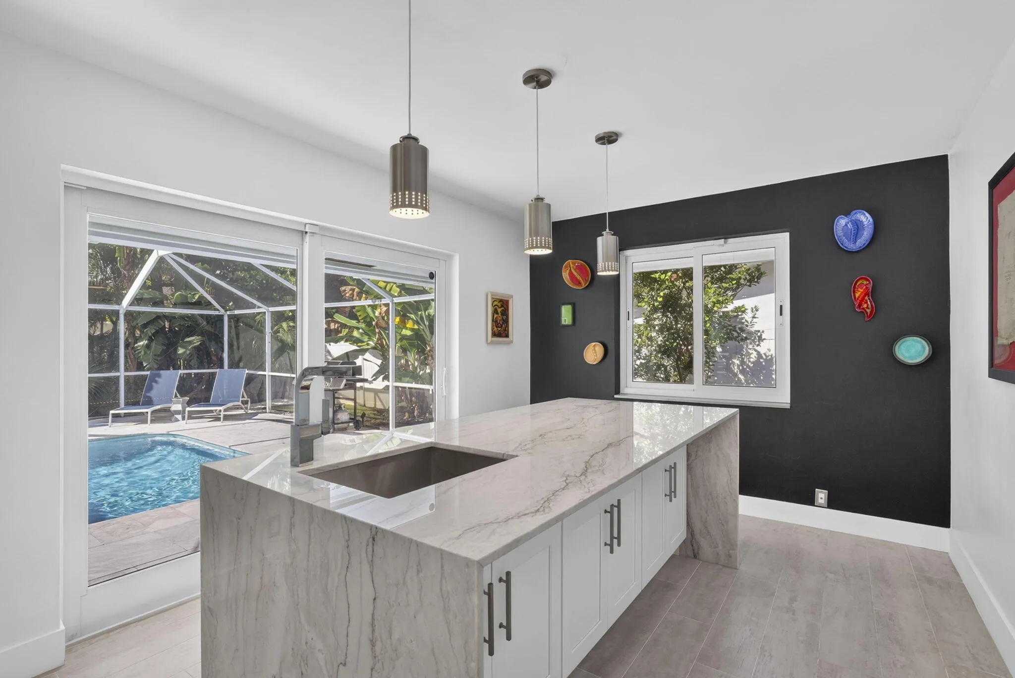 Spacious kitchen island with an undermount sink and a light-toned countertop, complemented by white cabinetry and dark hardware