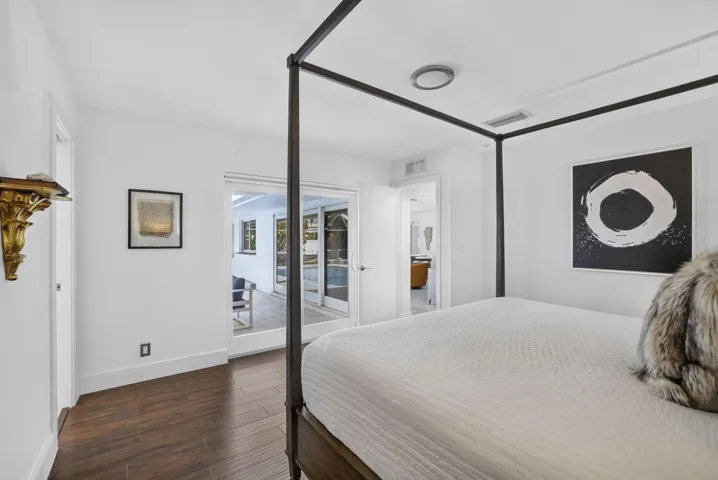 Wood-finish flooring, white walls, recessed ceiling lighting, and a doorway opening to an exterior patio
