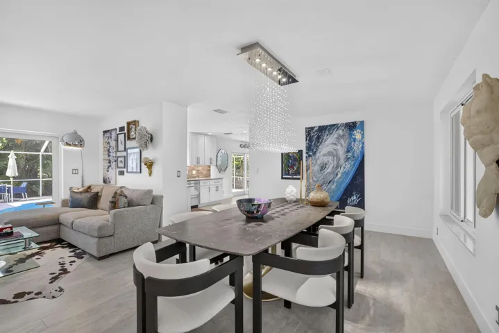 Open-concept living and dining area, a contemporary linear crystal chandelier, and a sliding glass door leading to an outdoor space