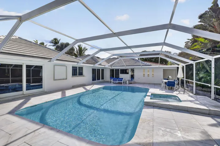 Screened-in outdoor living space featuring a rectangular pool and integrated spa