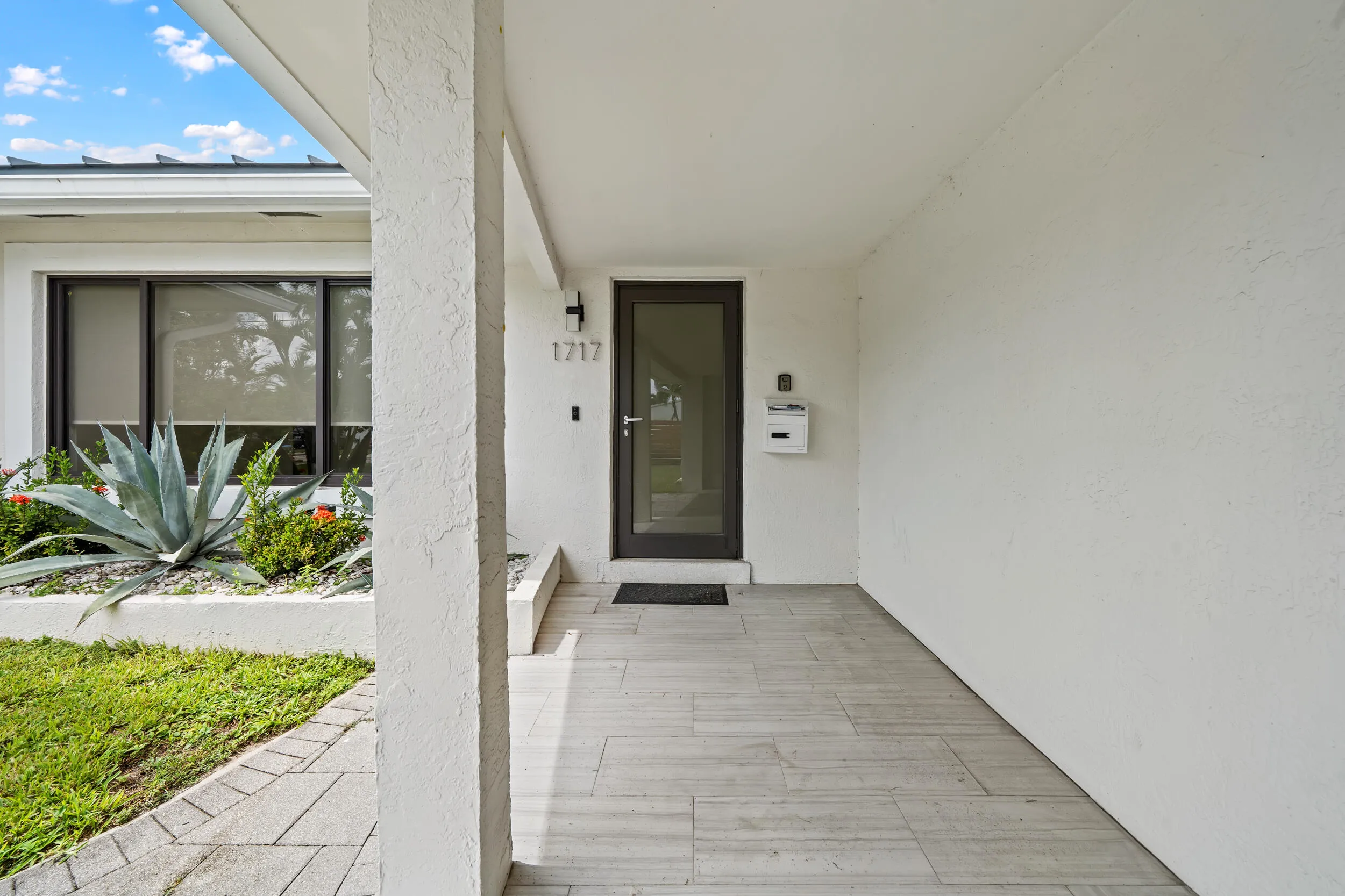 Covered entryway with tile flooring, modern front door, and stucco exterior