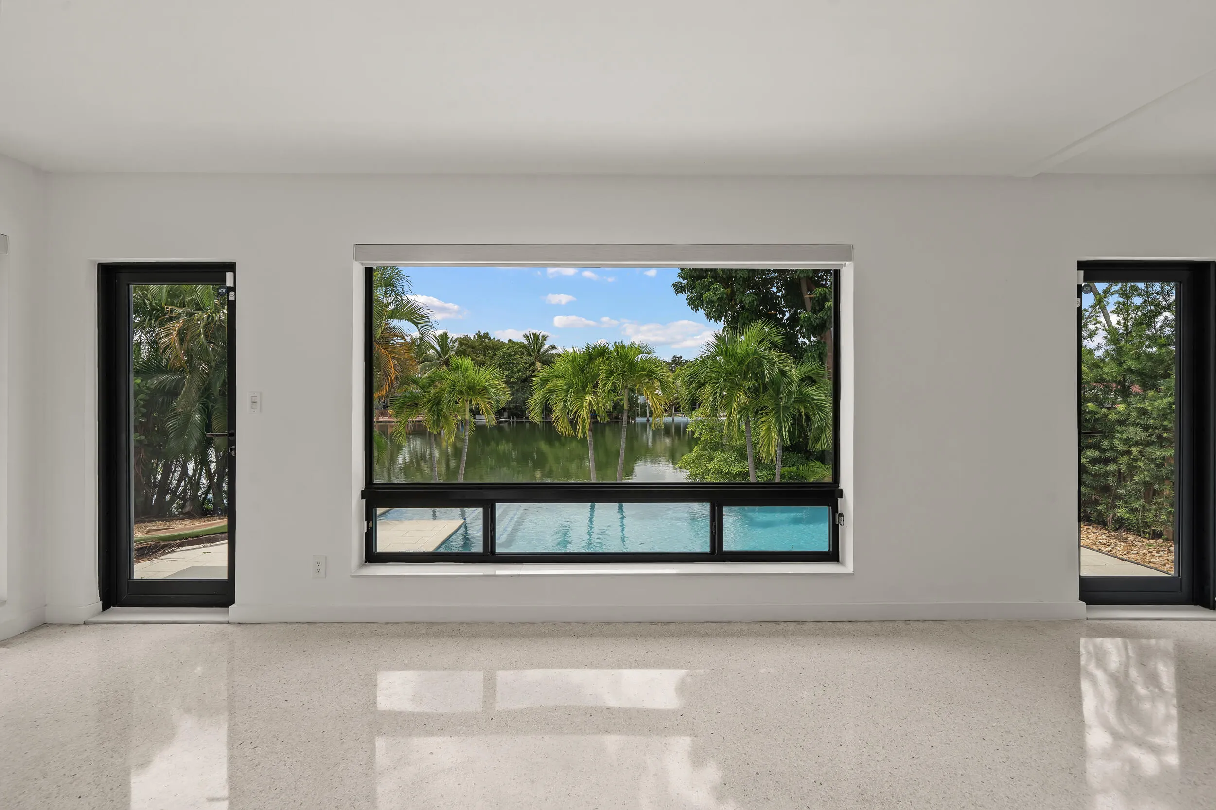 Reflective terrazzo flooring, expansive windows, and two glass-paneled exterior doors