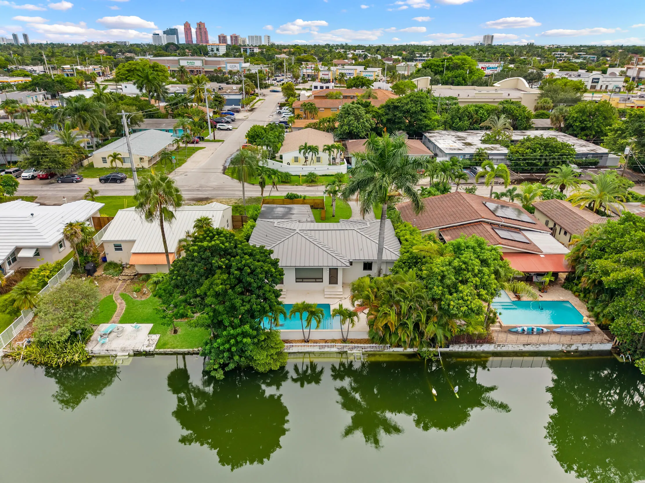 Waterfront property featuring a private swimming pool, mature tropical landscaping, and a manicured lawn