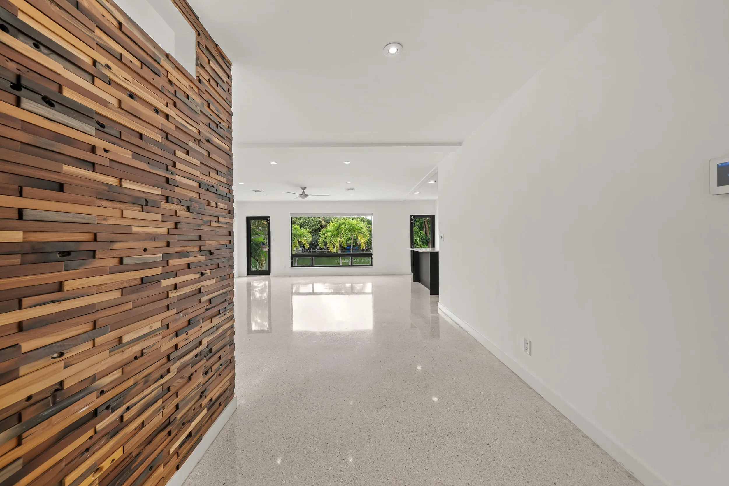 Wood-paneled accent wall, recessed lighting, polished flooring, contemporary ceiling fan, and black framed windows